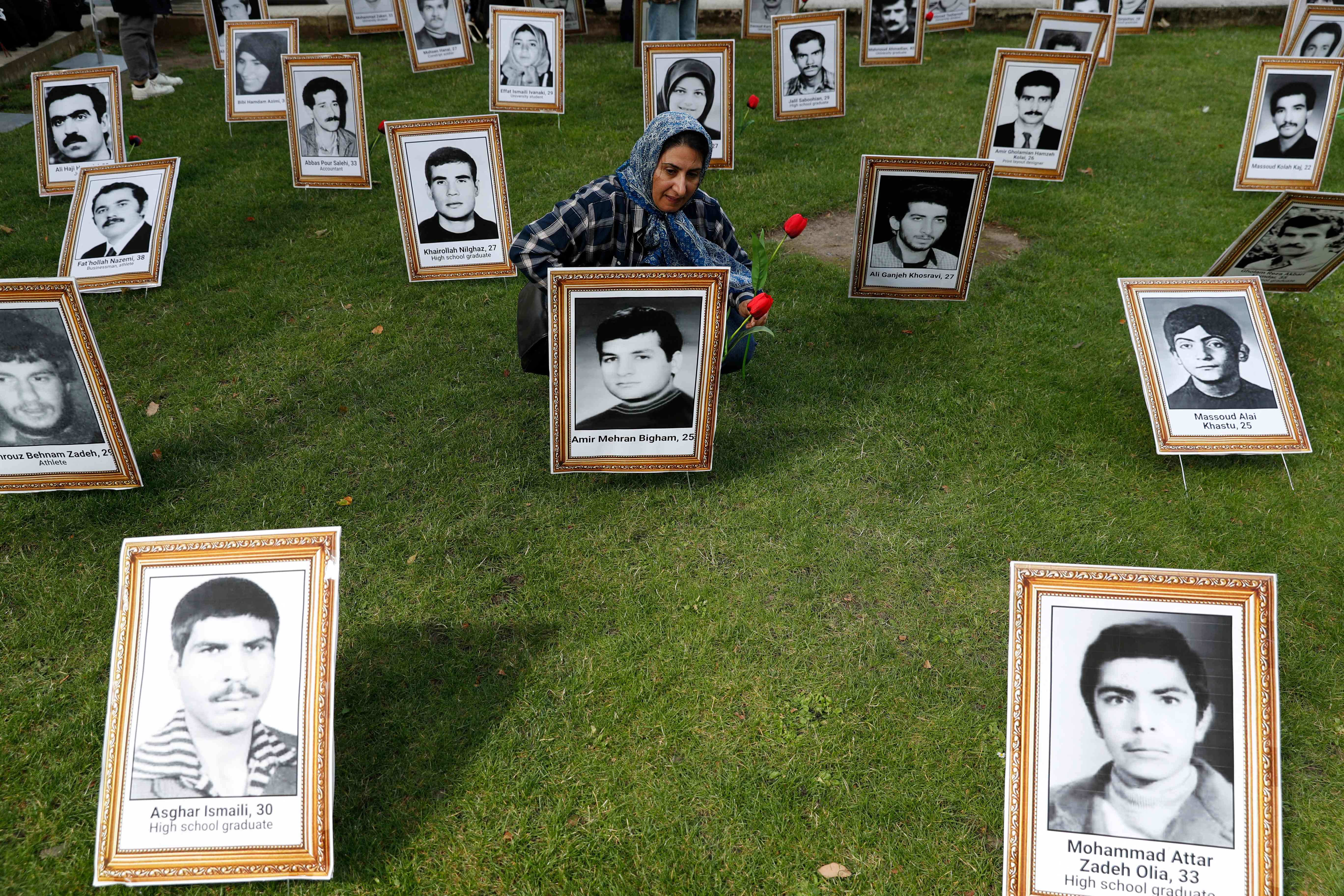 A protester places flowers on a photograph of an executed man during a demonstration to protest against the inaugeration Ebrahim Raisi in London in 2021