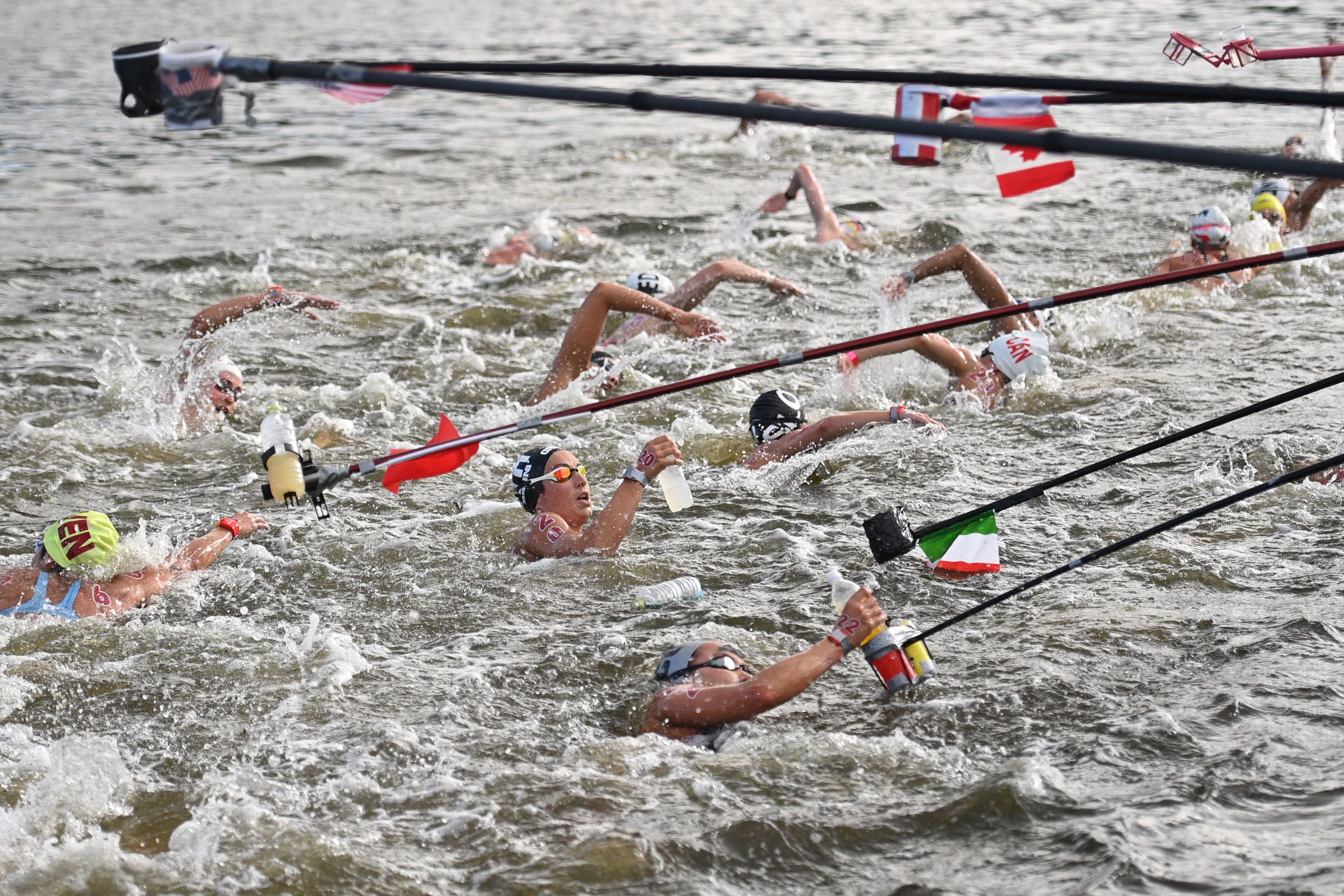 Italy's Rachele Bruni (C) takes refreshment at a feed station along the course during the women's 10km marathon swimming event during the Tokyo 2020 Olympic Games at the Odaiba Marine Park in Tokyo on August 4, 2021.