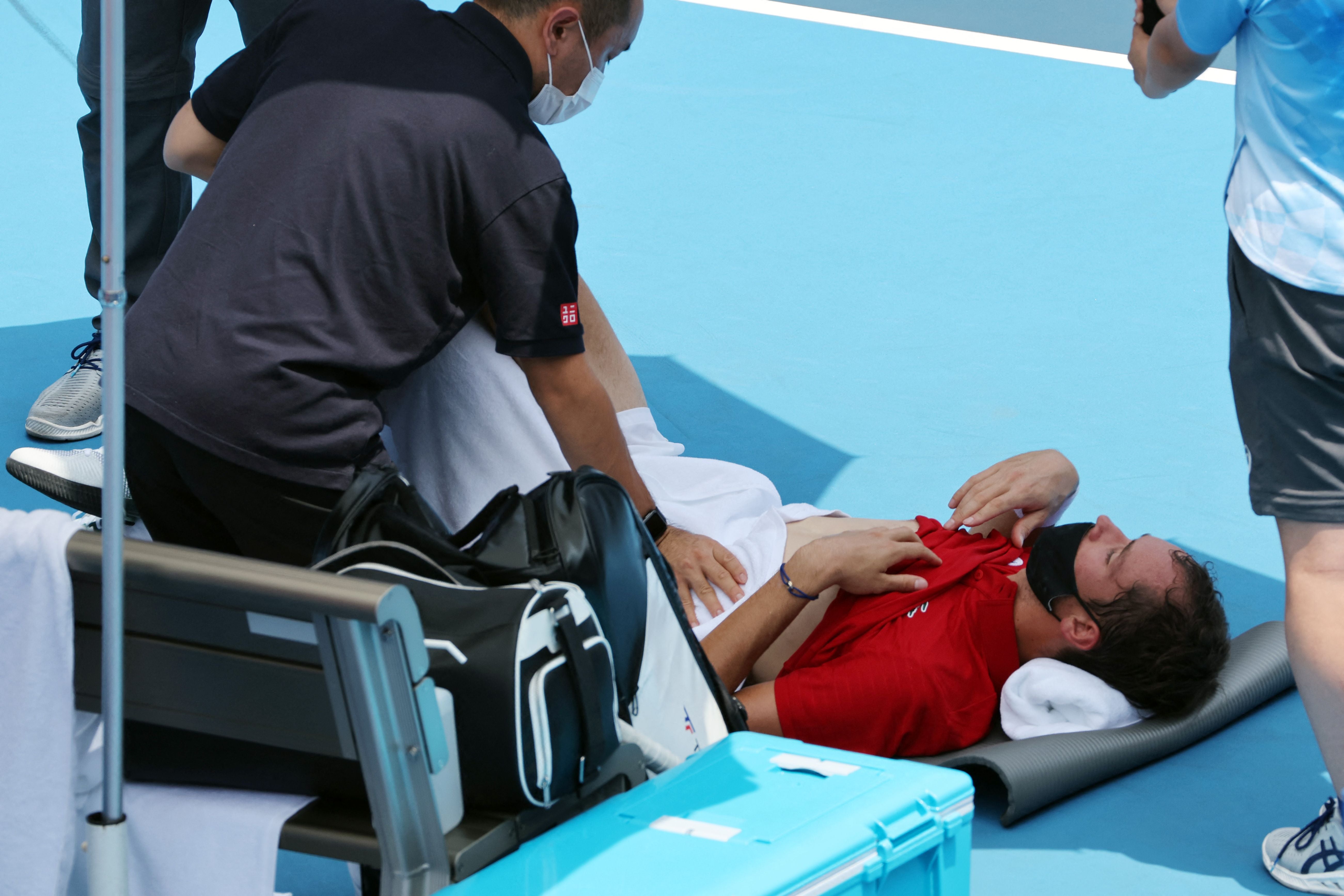 Russia’s Daniil Medvedev is assisted by a physio after suffering from the heat at the Ariake Tennis Park