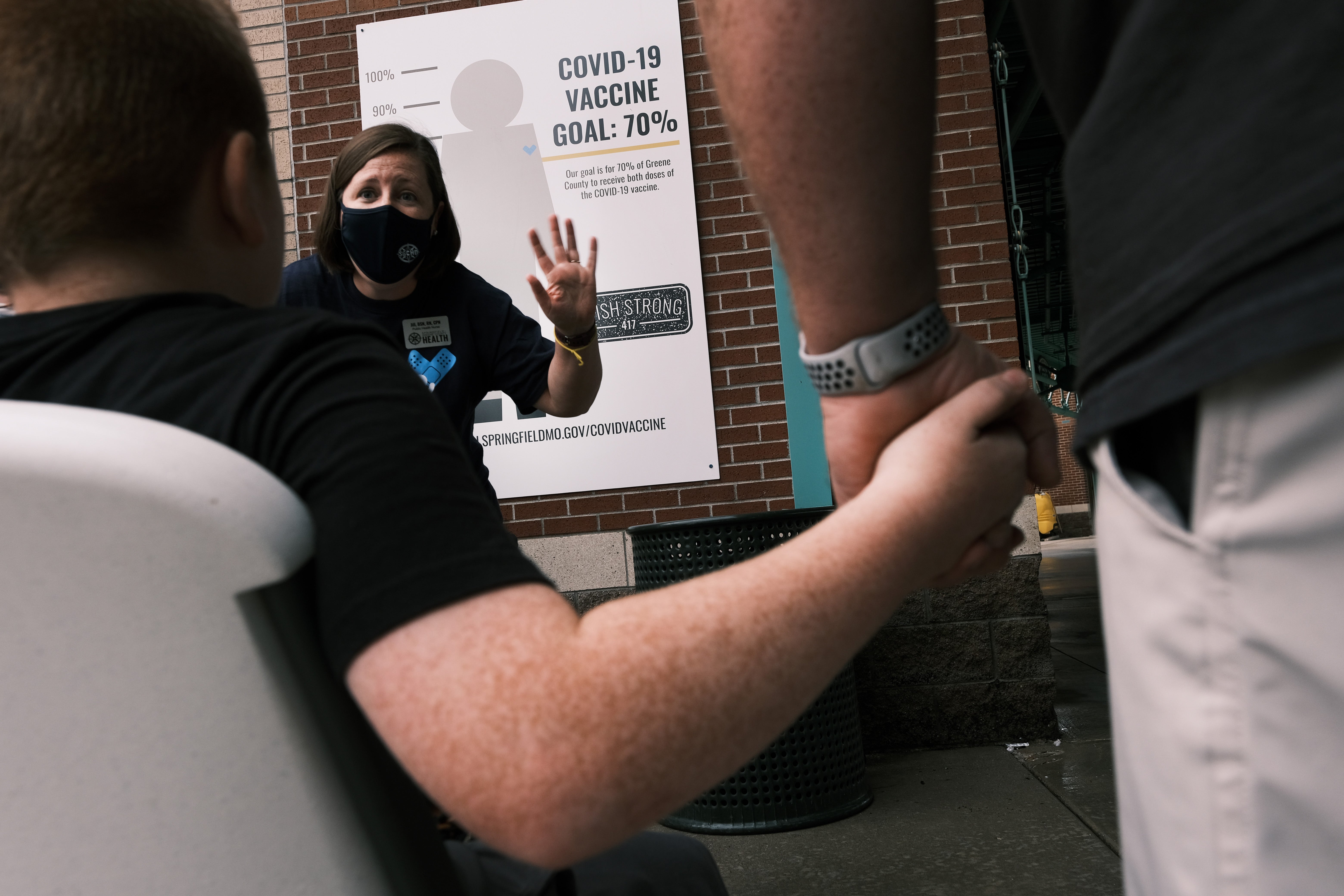 File. A boy holds his father's hand as he receives the Covid vaccine at a baseball game in Springfield, Missouri, on 5 August 2021