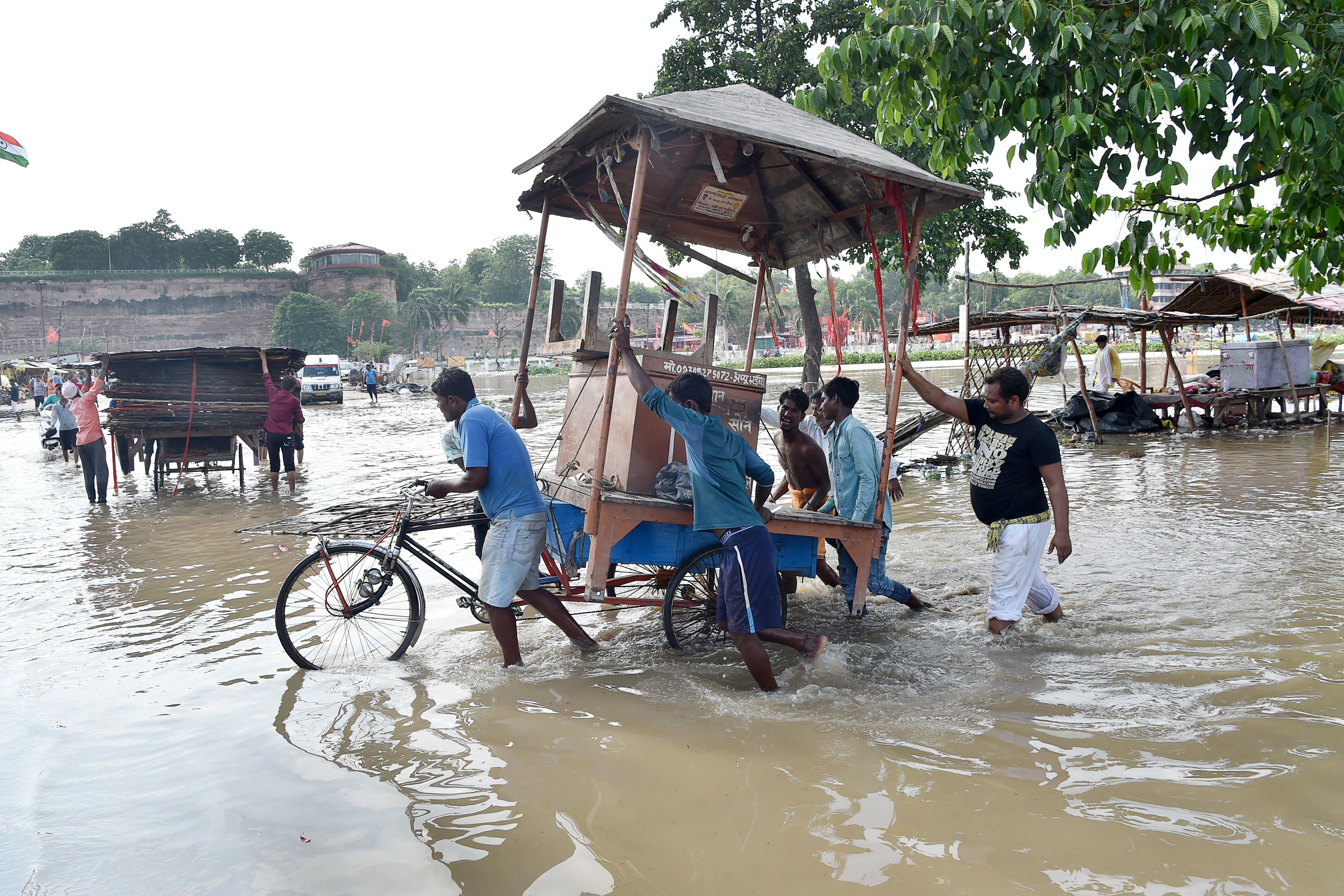 People move their belongings from a flooded area on the banks of the River Ganges in Allahabad on 4 August 2021