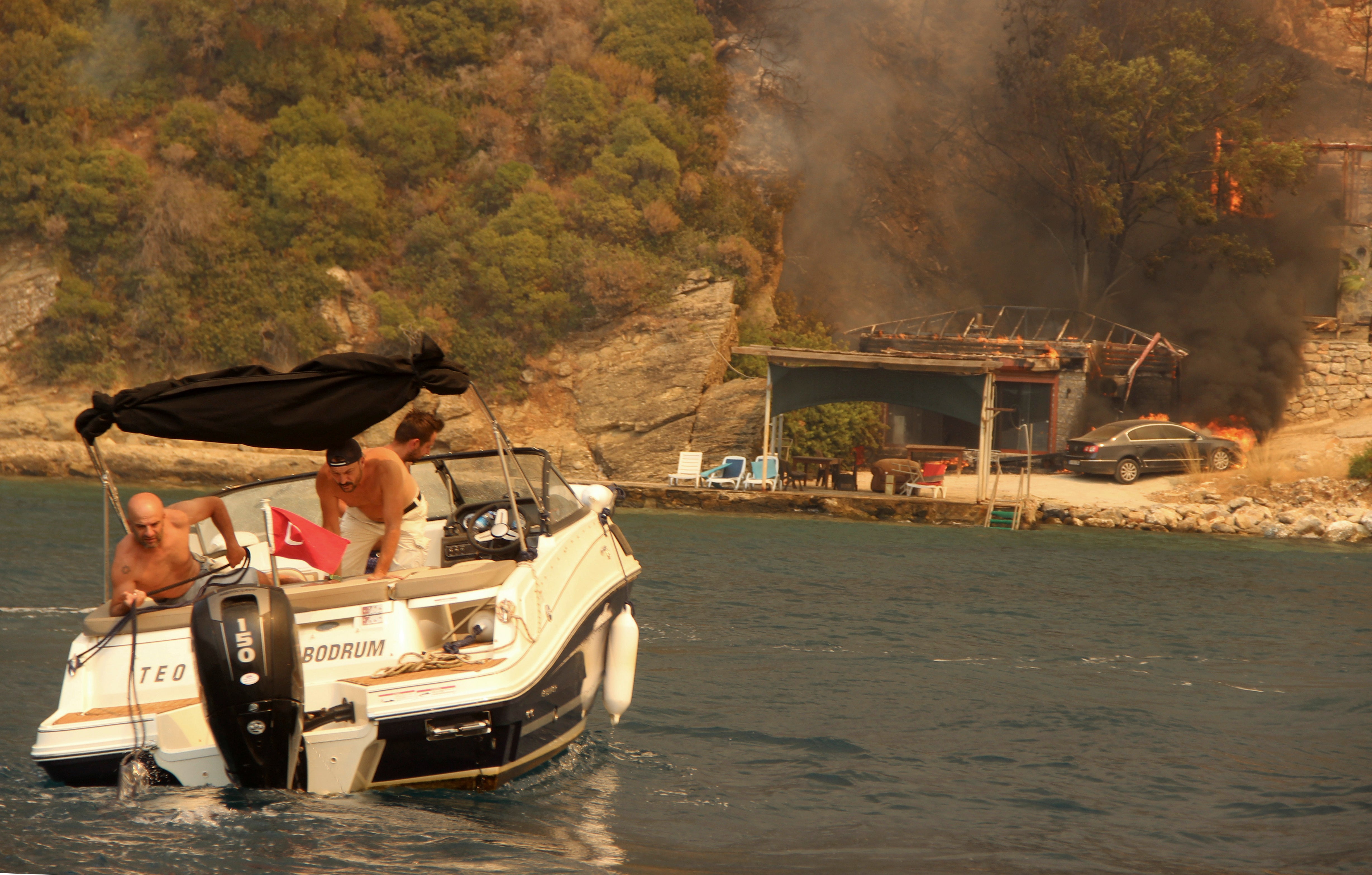 People use a boat to evacuate from smoke-engulfed Mazi area