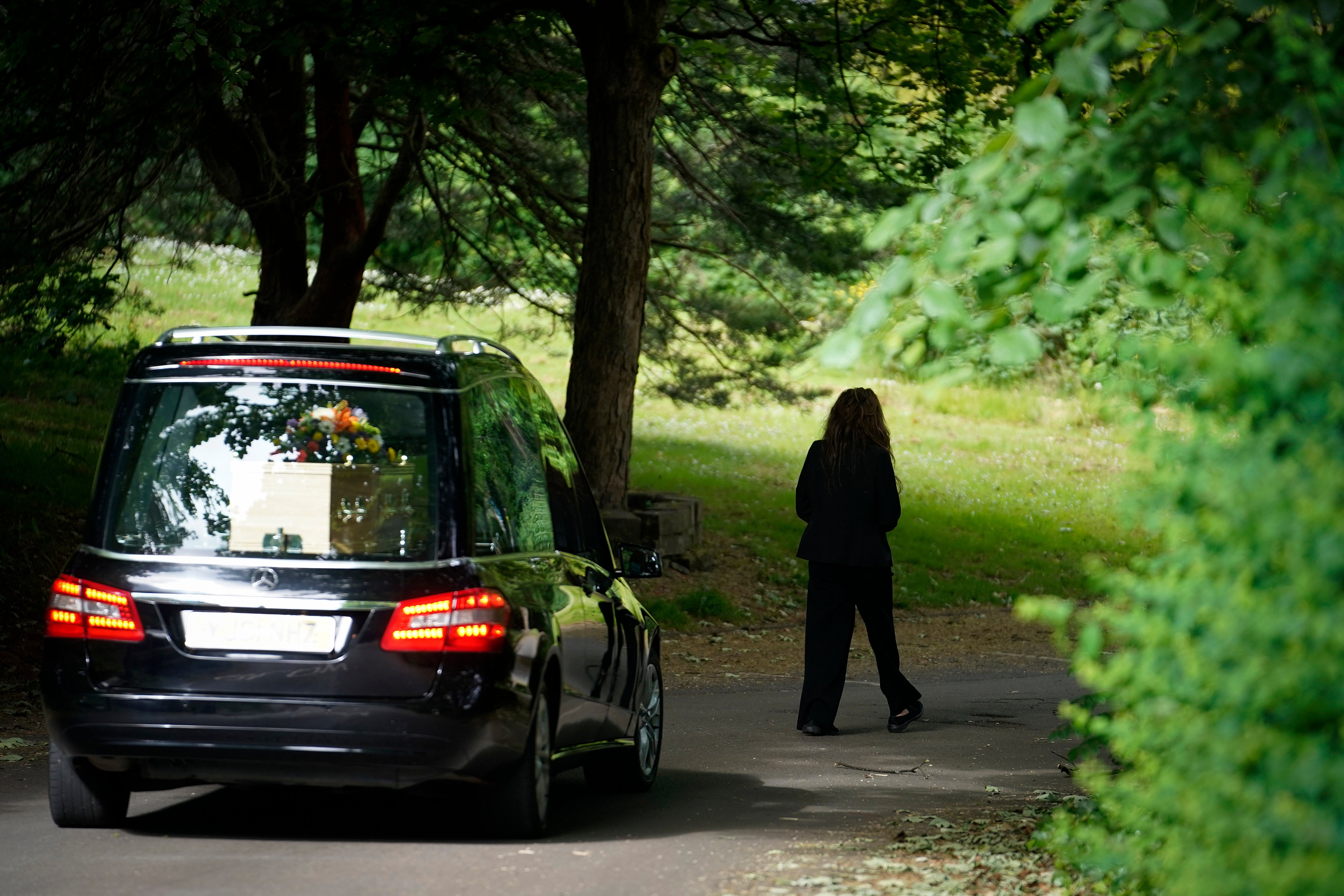 Standard service: the funeral director leads the hearse carrying the casket