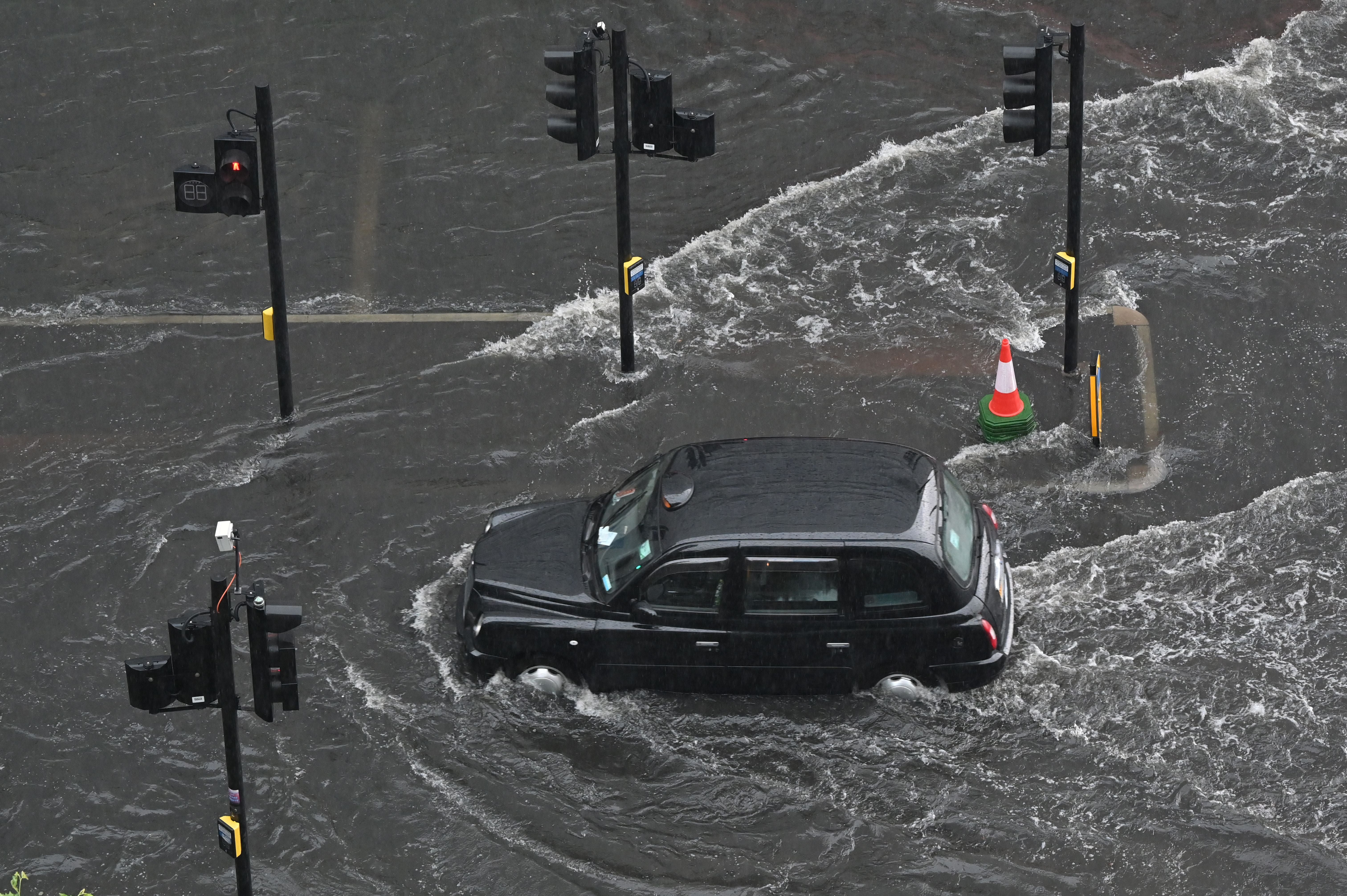 A London taxi struggles to drive though floodwaters