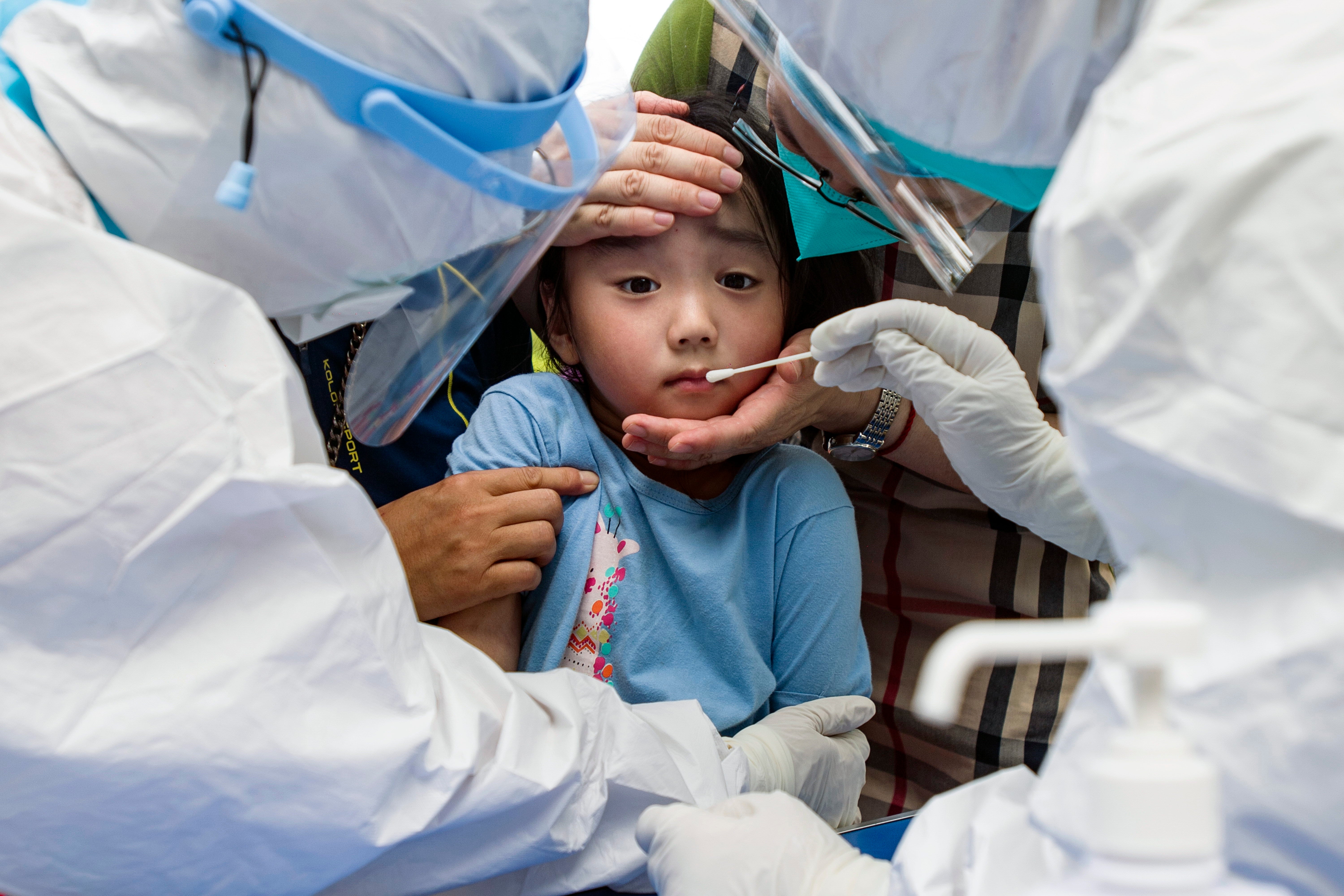 A child reacts to a throat swab during mass testing for Covid-19 in Wuhan in central China’s Hubei province