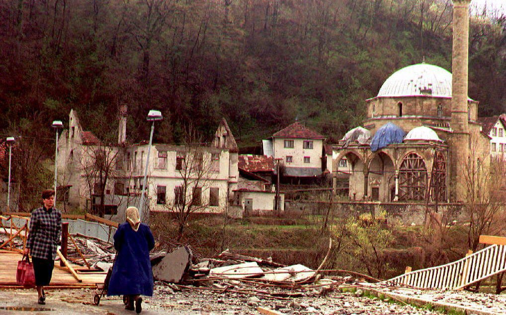 Two women pass a bridge and the mosque of Maglaj damaged by Serb artillery fire, 27 March 1994. The siege of this mainly Muslim enclave was lifted the previous week