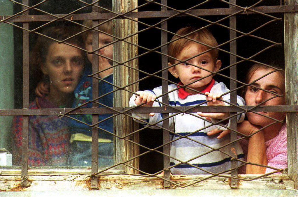 Bosnian Muslim refugees look out a window of a school building as about 250 new refugees arrive in Travnik from the Serb-controlled town of Banja Luka and surrounding villages, 7 July 1993