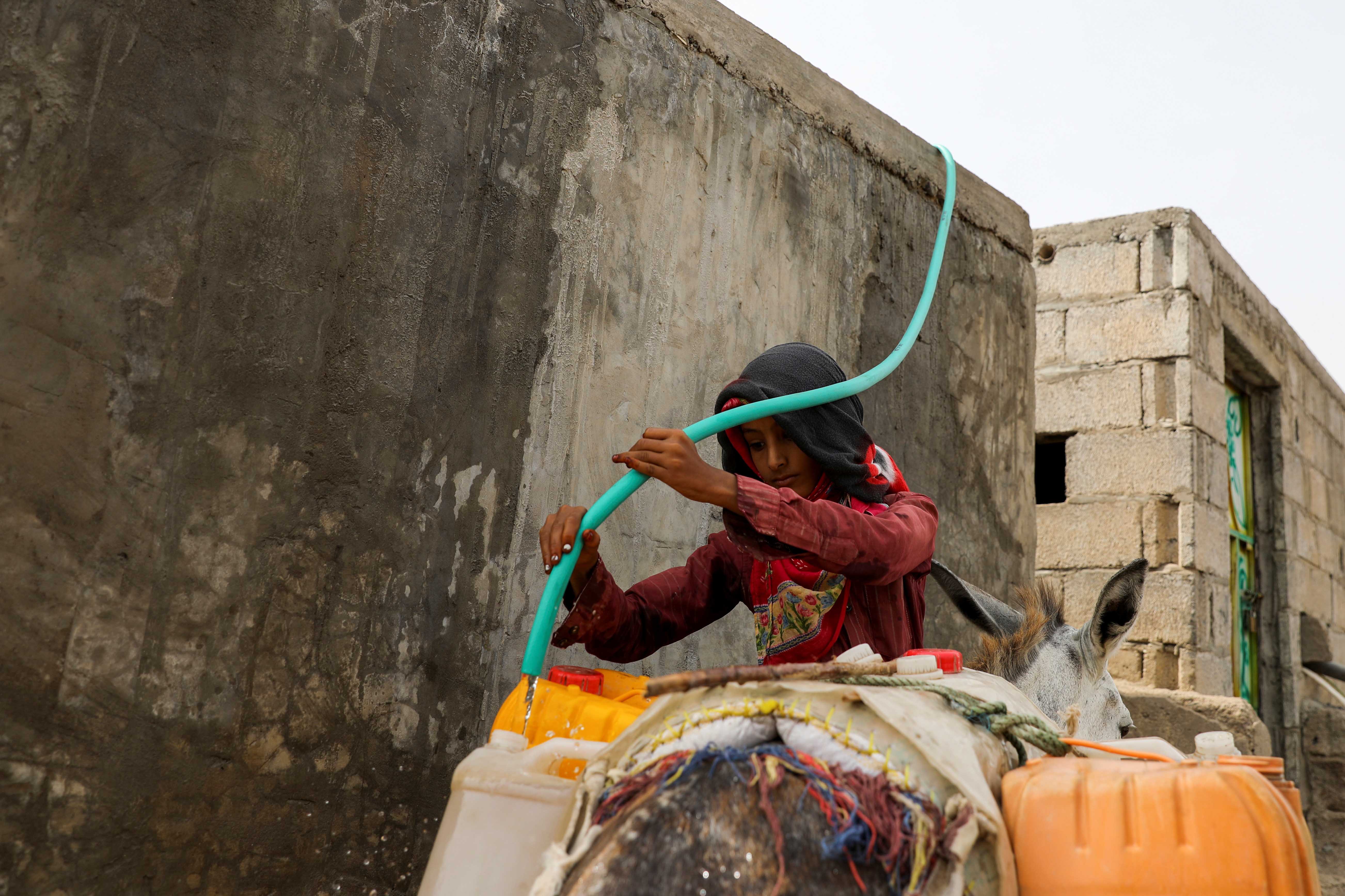 A girl fills jerry cans with water from a well in Bajil district of Hodeida province