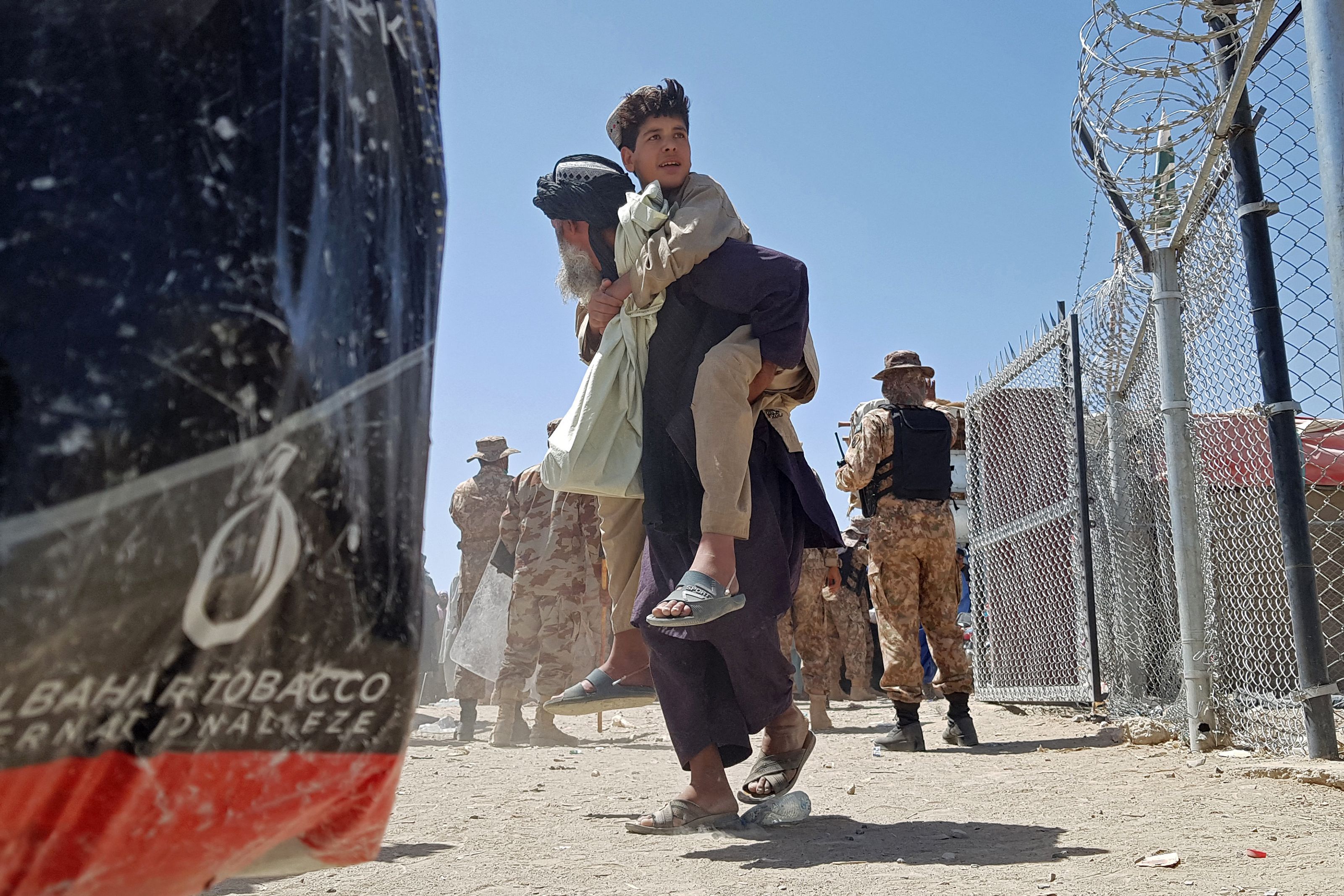 A stranded Afghan carries his son at the Pakistan-Afghanistan border crossing point in Chaman