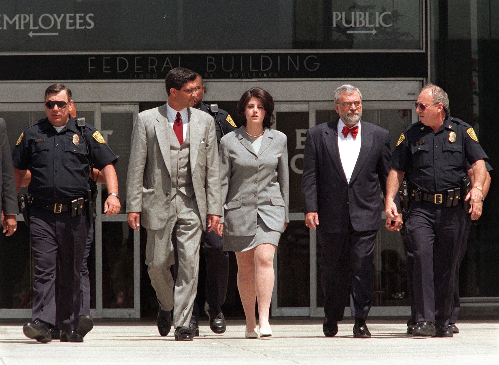 Monica Lewinsky (center) is escorted by police officers, federal Investigators, and her attorney William Ginsburg as she leaves the Federal Building on 28 May 1998 in Westwood, California, after submitting new evidence to Ken Starr’s office