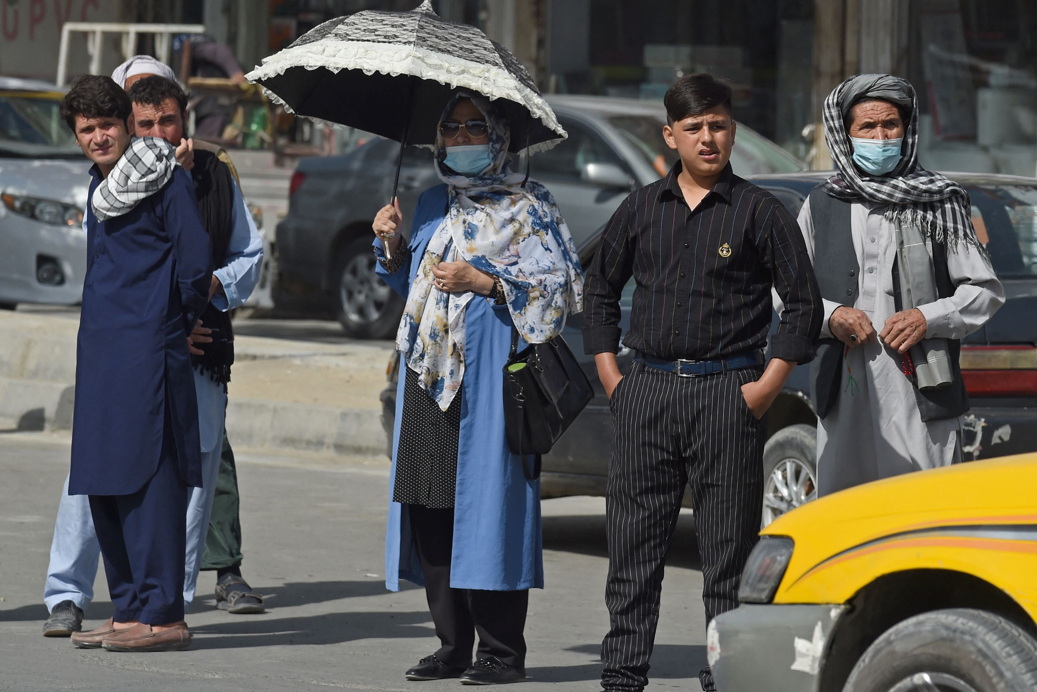 Afghan people stand along the roadside as they wait for taxis in Kabul yesterday