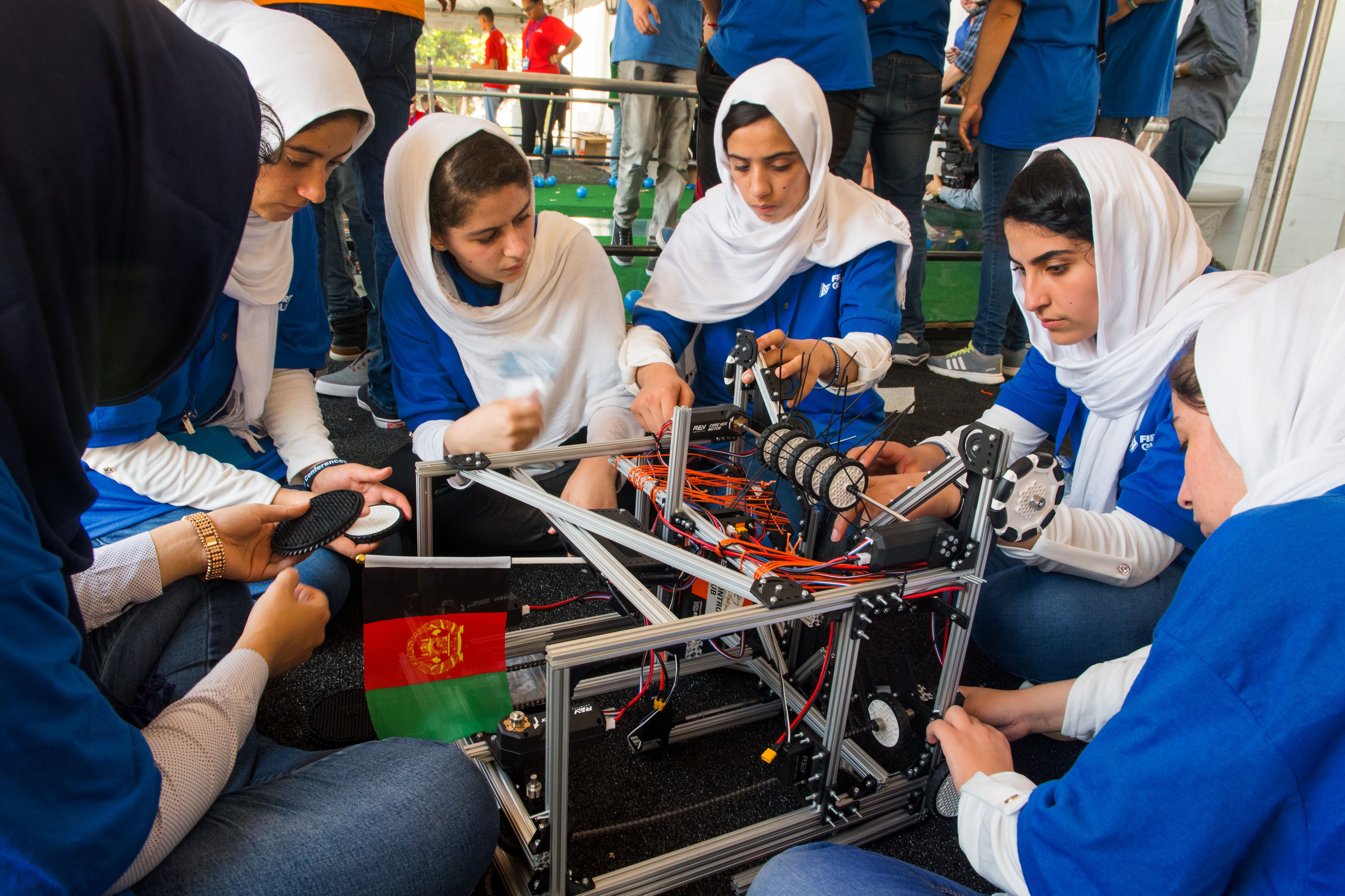 Members of the Afghan all-girls robotics team make adjustments to the team robot in the practice area in 2017