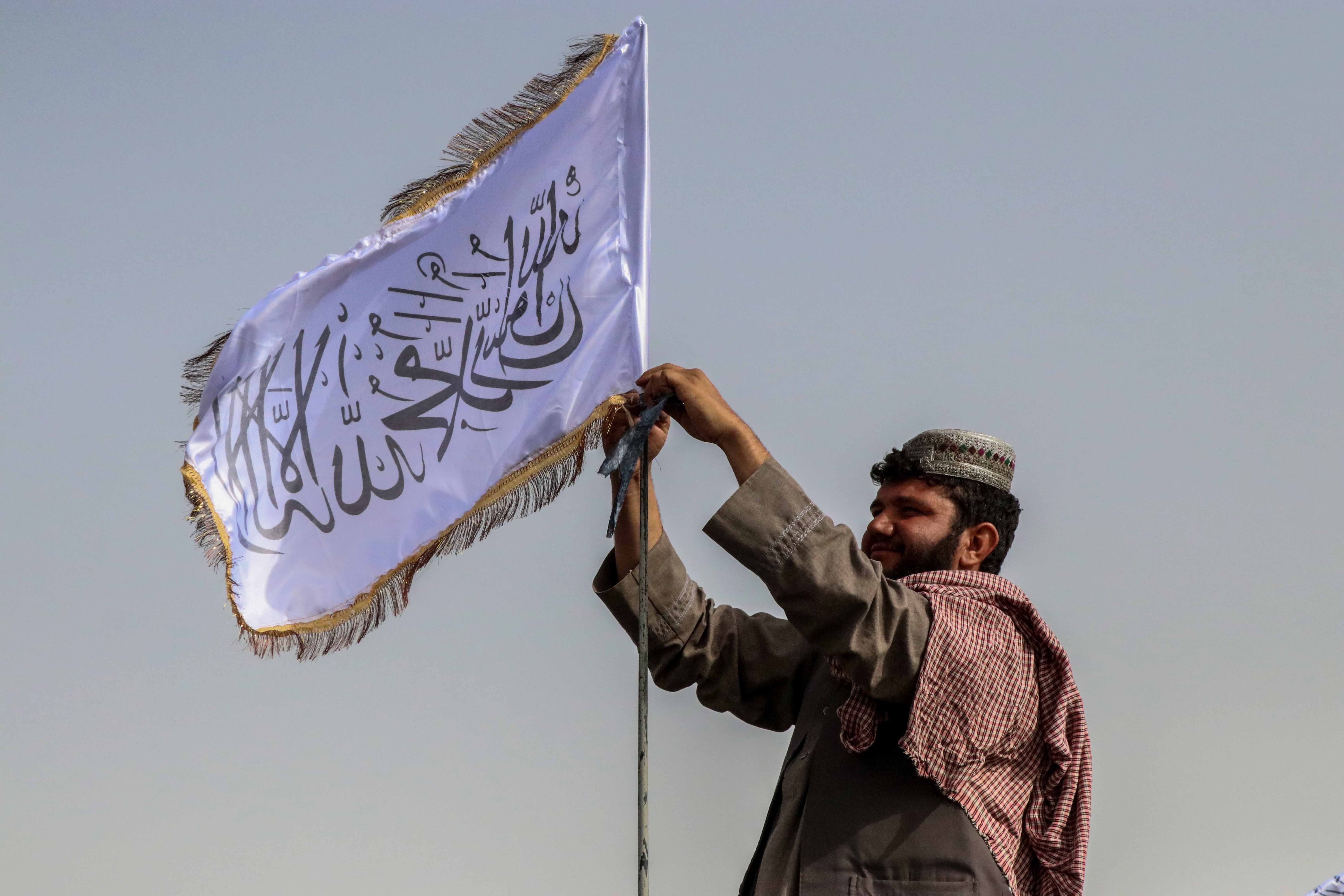 A Taliban fighter raises their flag on a vehicle as they patrol in Kandahar, Afghanistan, 17 August 2021.