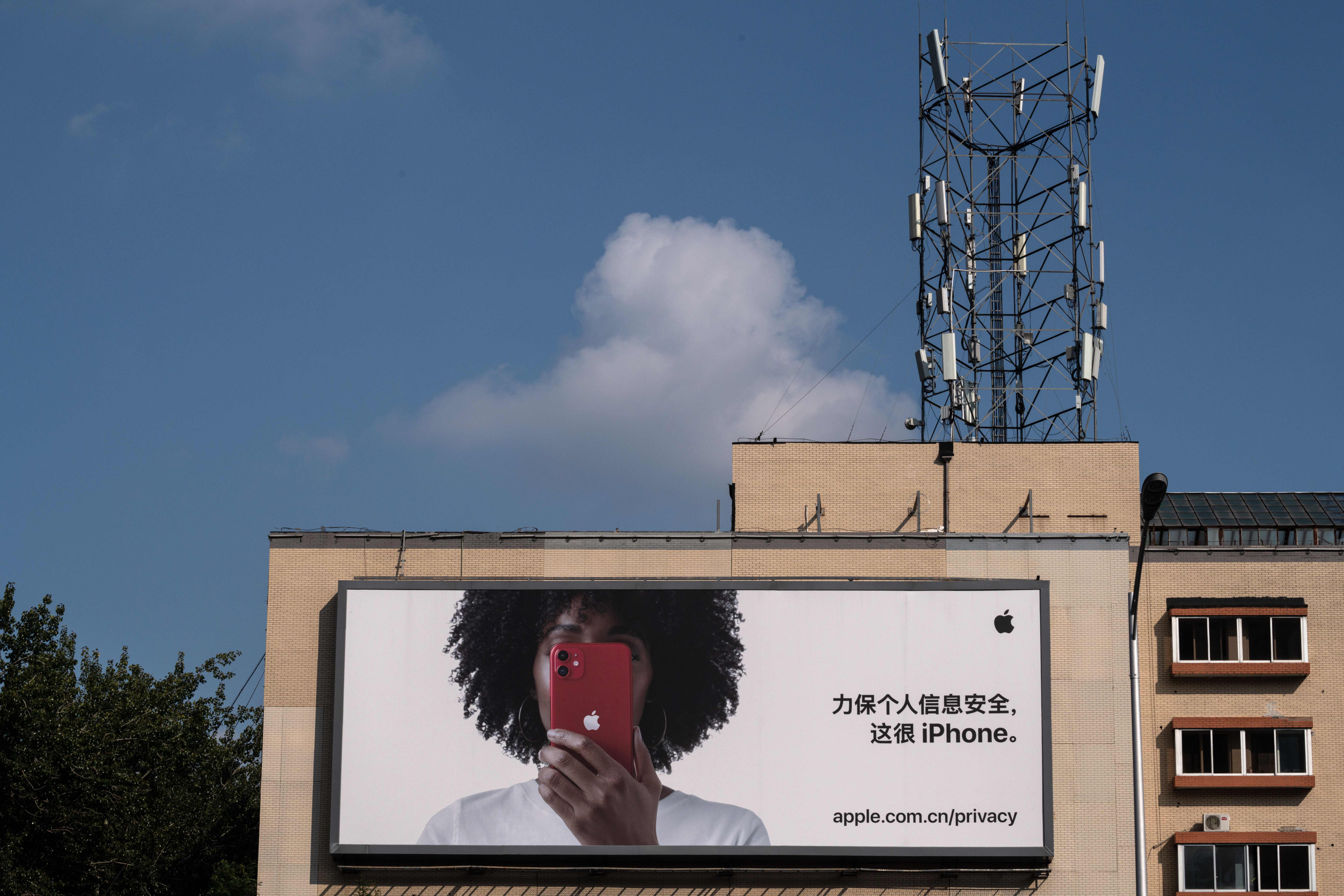 A cellphone tower on top of a building is seen next to a commercial billboard for the iPhone in Beijing