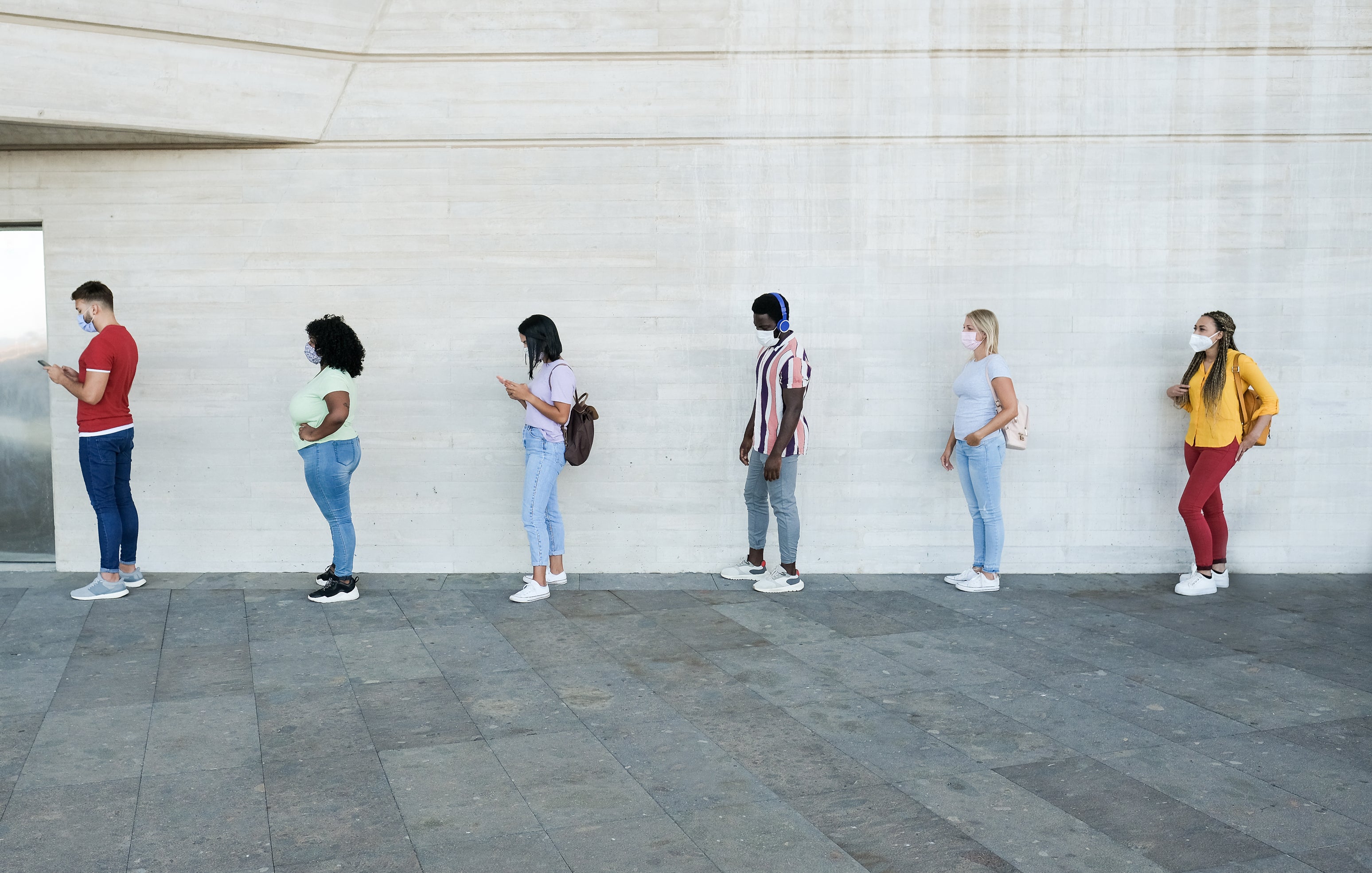 PEople stand in a socially-distanced queue