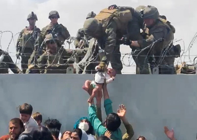 A baby is handed over to the American army over the perimeter wall of Kabul airport on Thursday