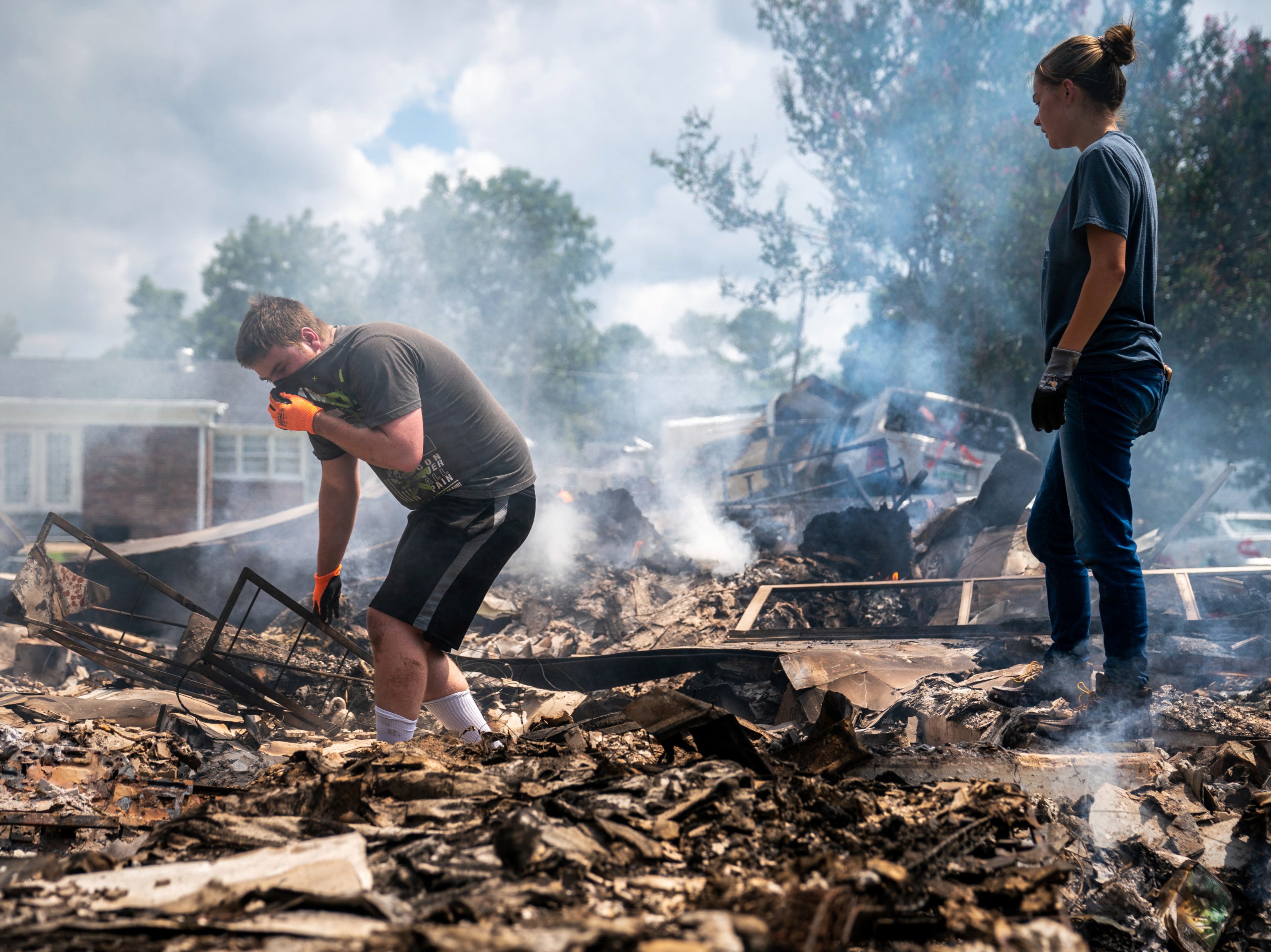 Josh Whitlock and Stacy Mathieson look through what is left of their home after it burned following flooding in Waverly, Tennesse on Sunday 22 August 2021