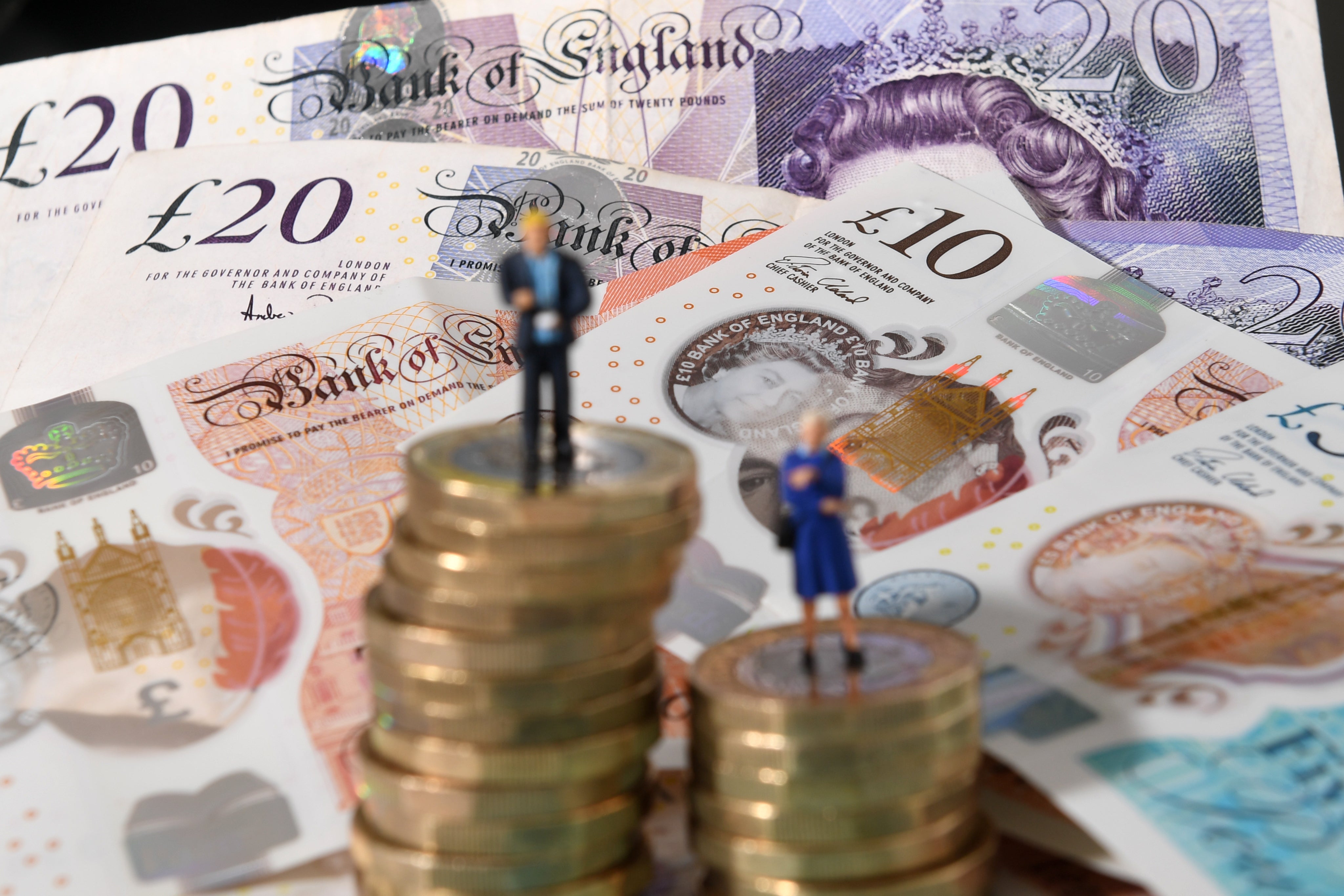 Models of a man and woman stand on a pile of coins and bank notes (Joe Giddens/PA)