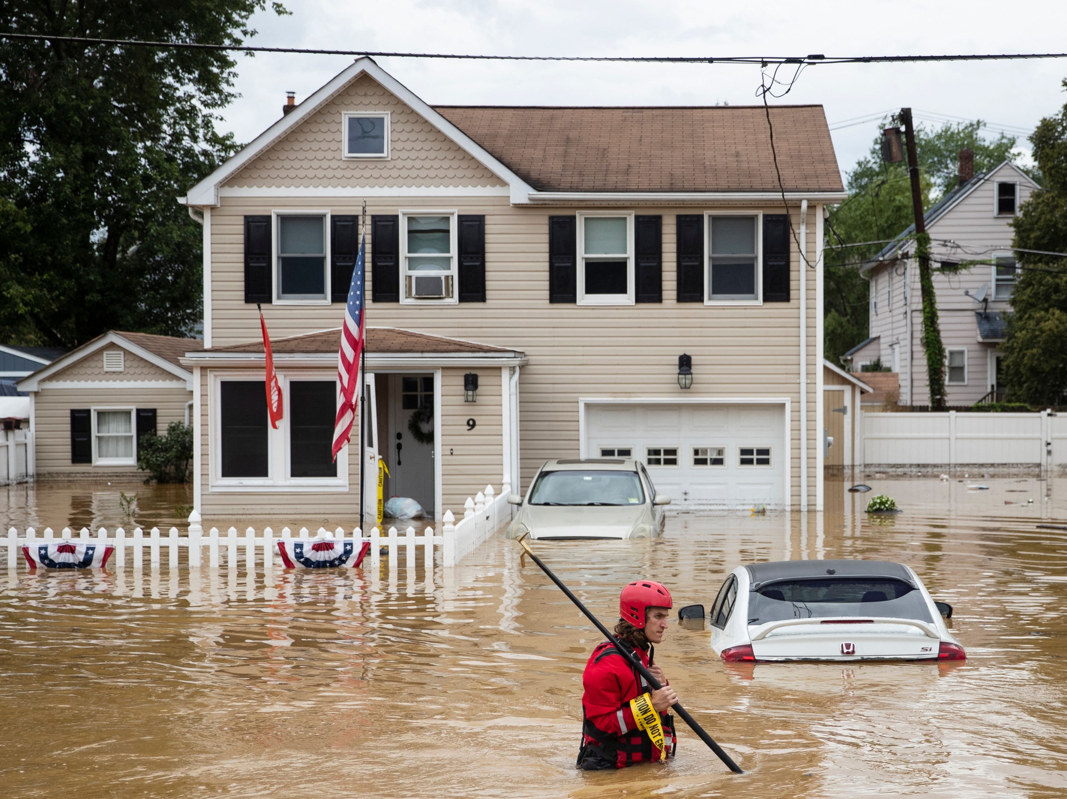 A New Market Volunteer Fire Company rescue crew member wades through high waters following a flash flood, as Tropical Storm Henri makes landfall, in Helmetta, New Jersey