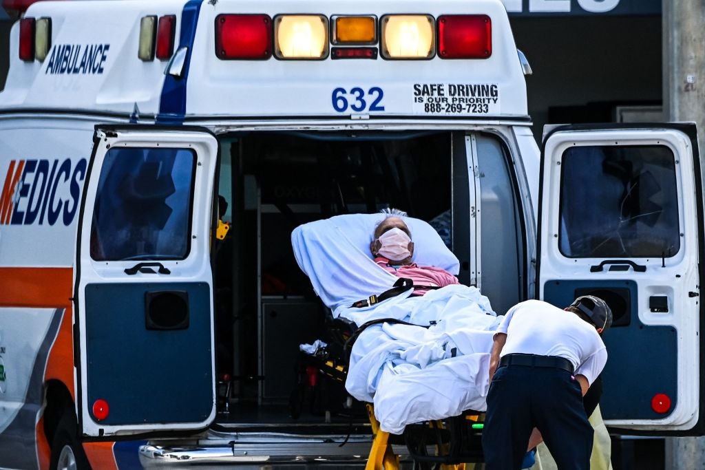 File: Medics transfer a patient on a stretcher from an ambulance outside of the emergency department at Coral Gables Hospital, Florida.