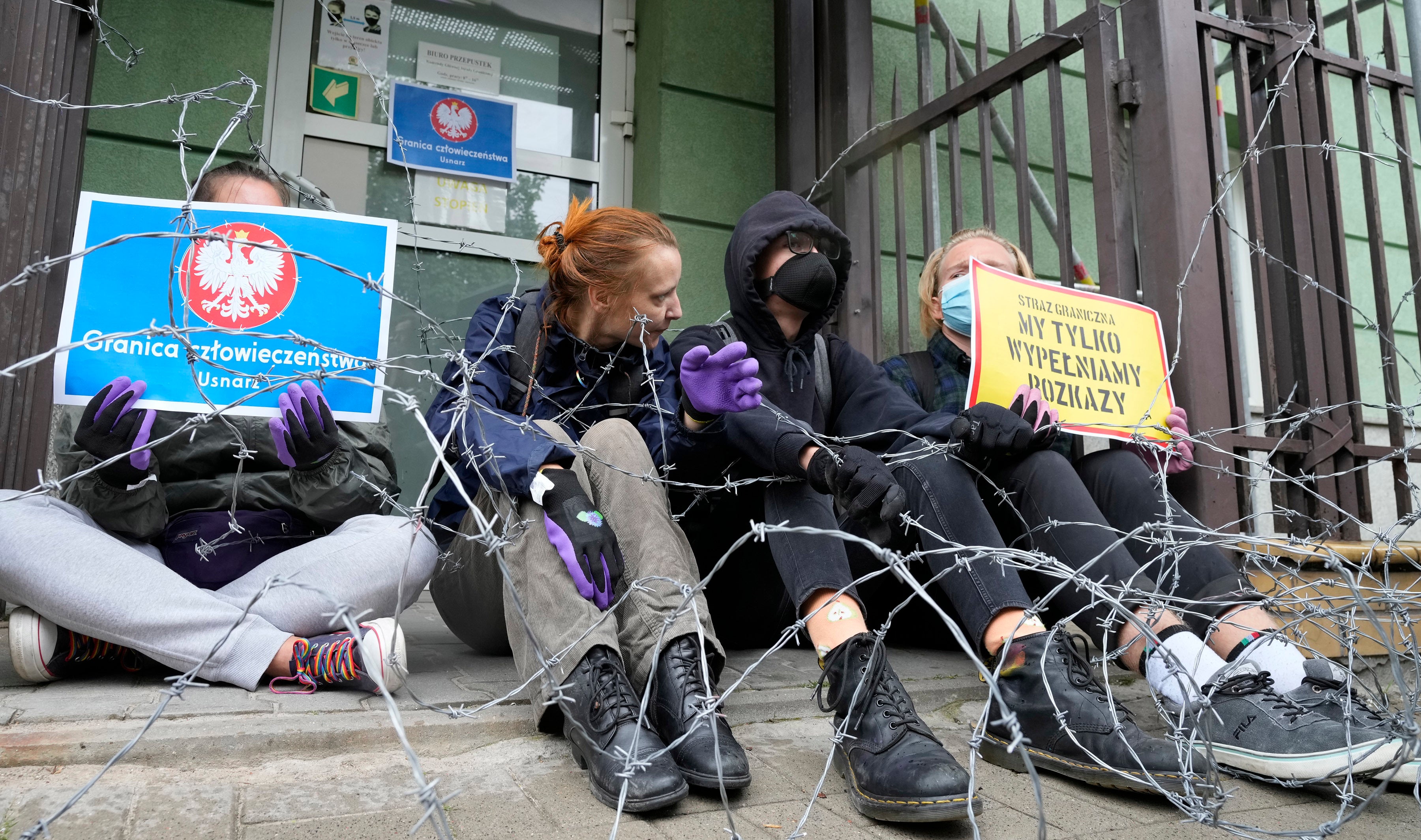 Protesters chained themselves to the fence surrounding the headquarters of Poland's Border Guards and put barbed wire on top of the fence to protest the government's refusal to let in a group of illegal migrants, in Warsaw