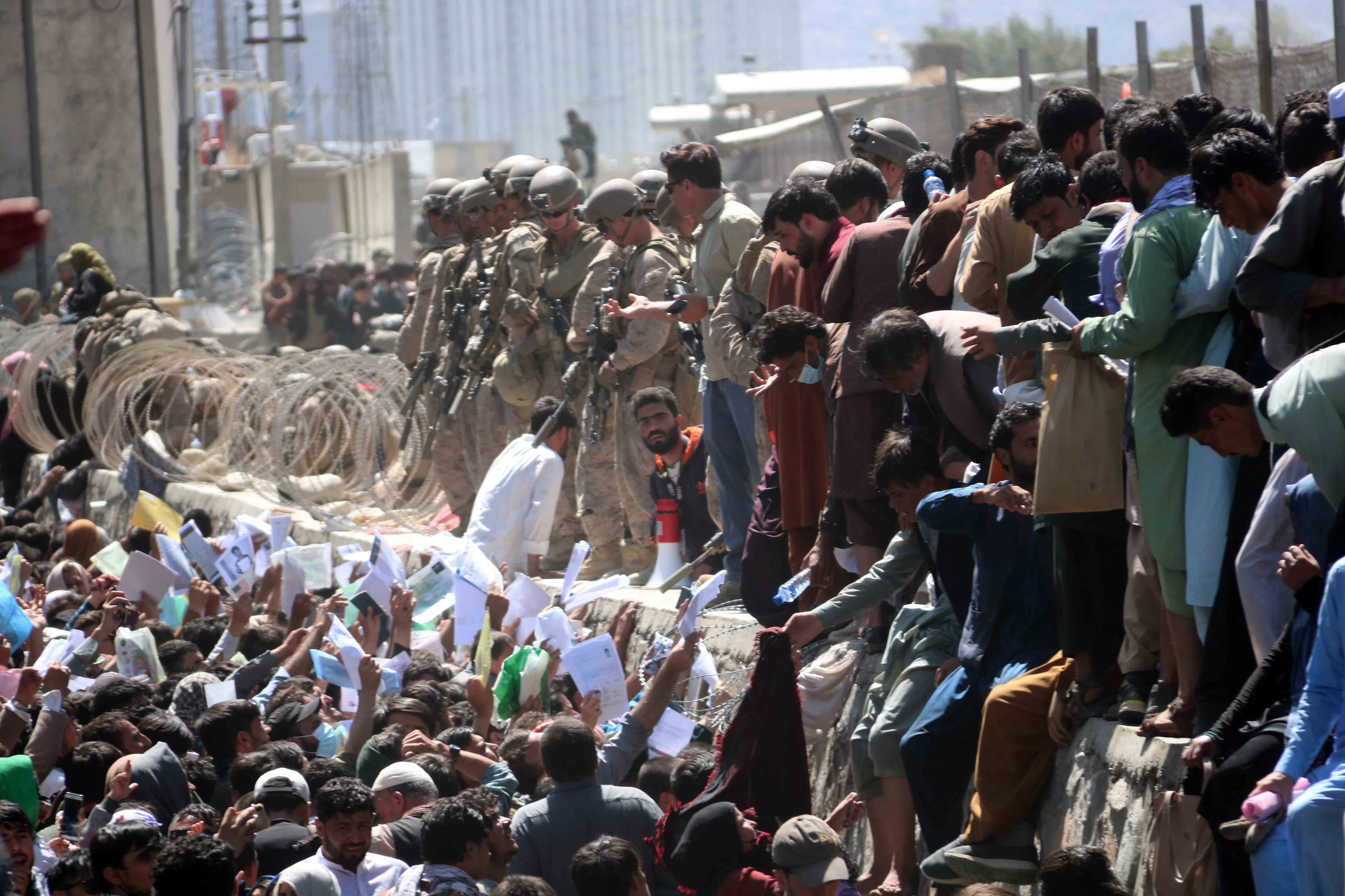 Afghans struggle to reach the foreign forces to show their credentials to flee the country outside the Hamid Karzai International Airport, in Kabul, Afghanistan