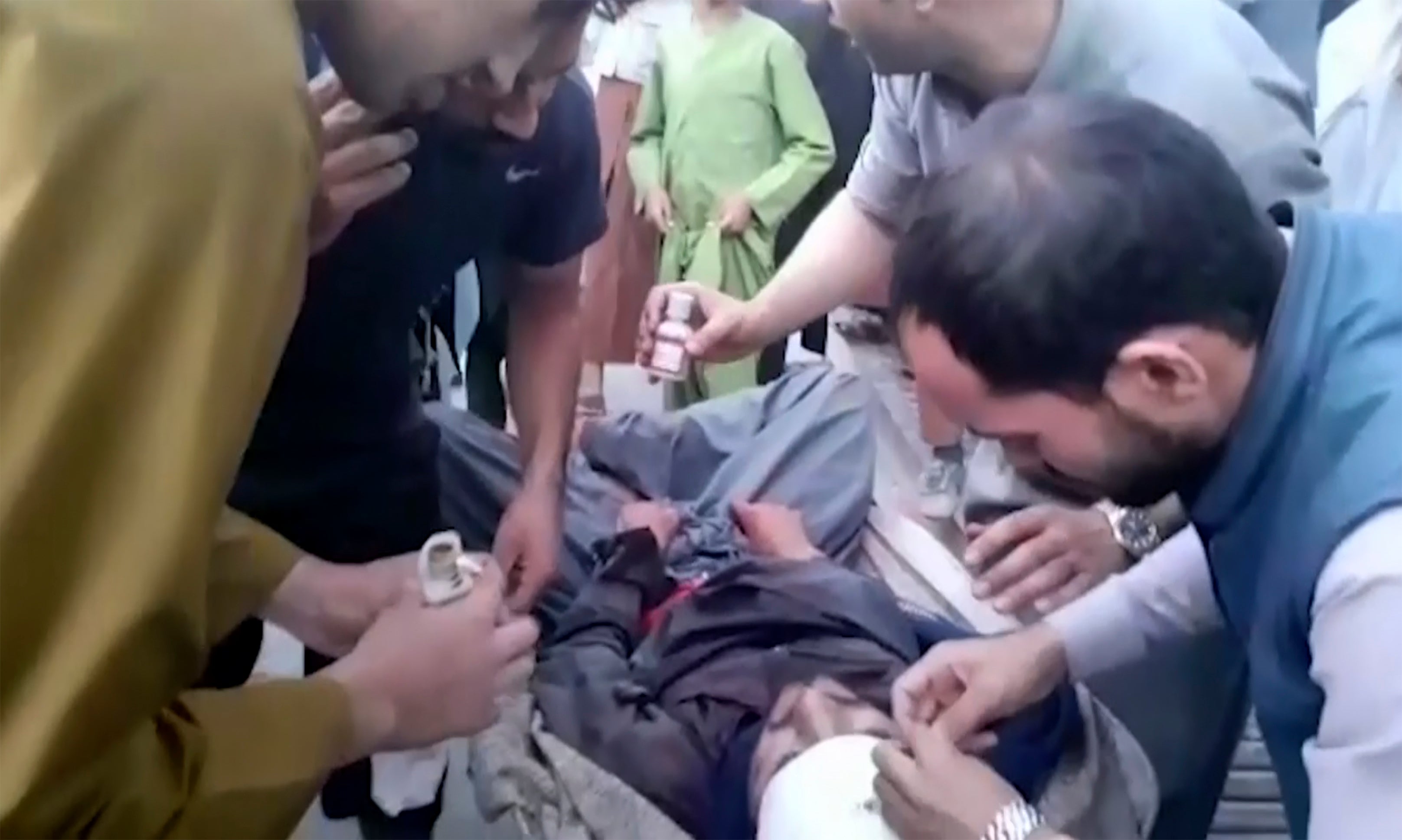 People tend to a wounded man near the site of a deadly explosion outside the airport in Kabul