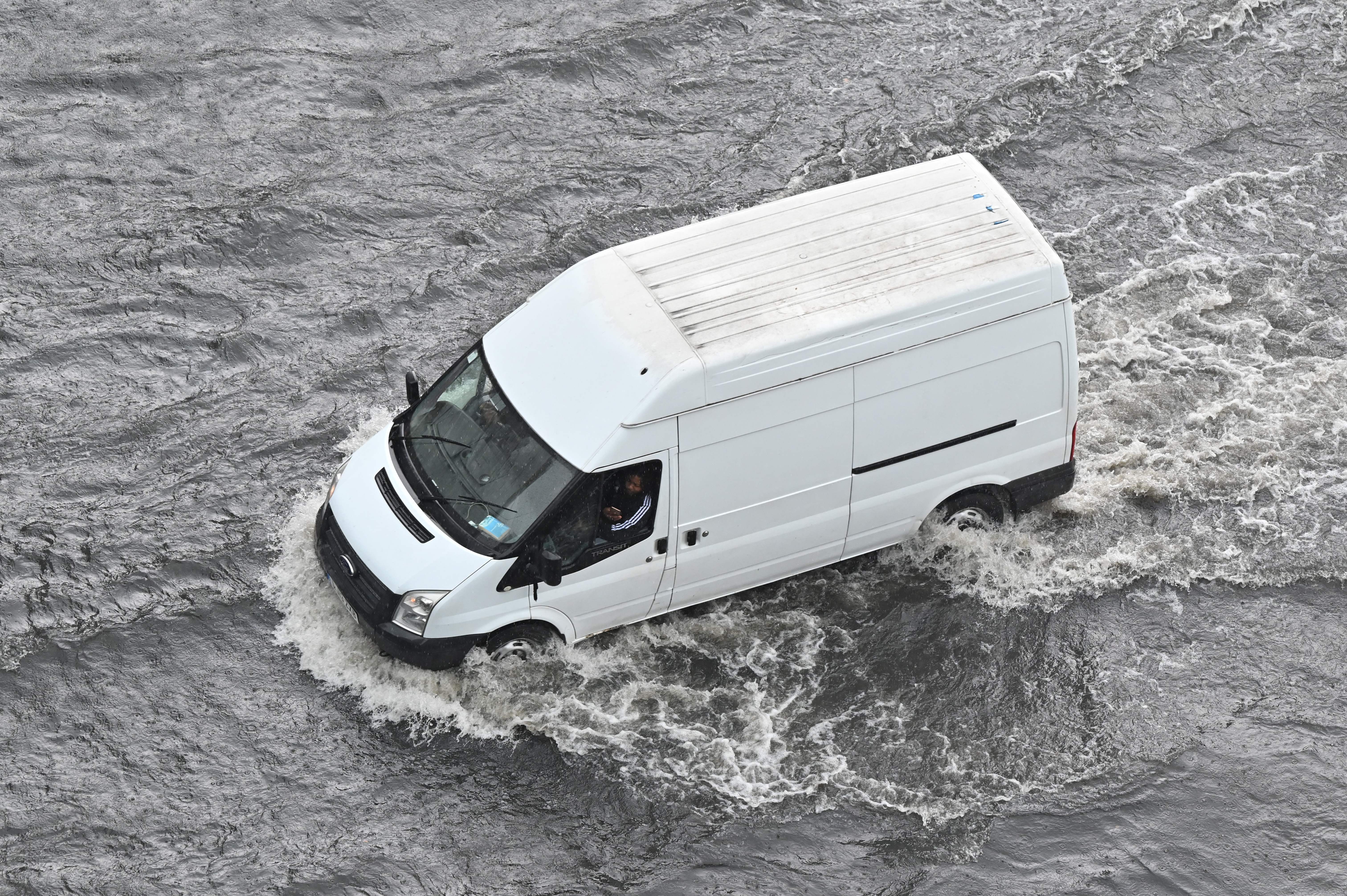 A van drives through water on a flooded road in London