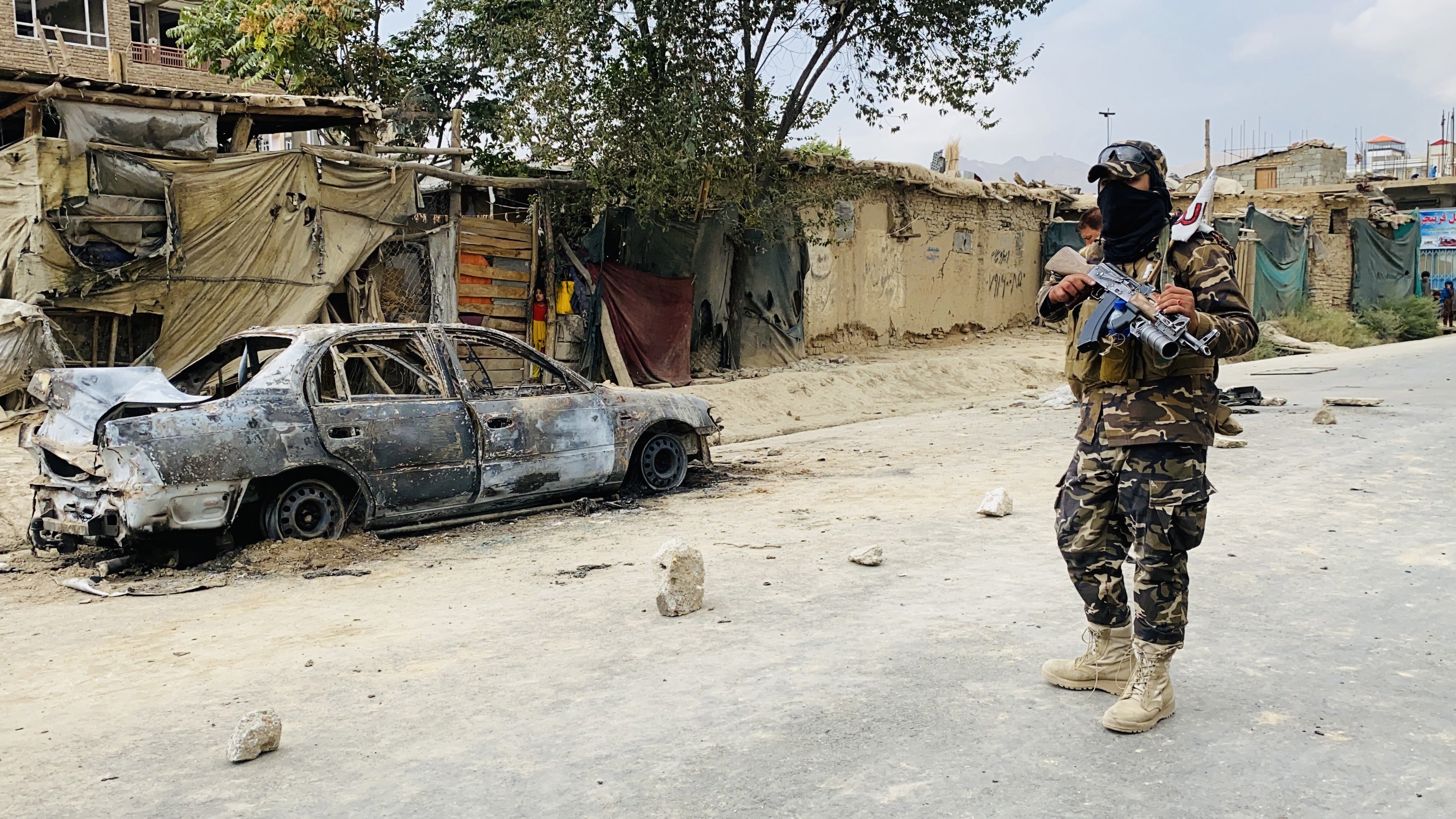 A member of the Taliban stands guard near a vehicle that was used to fire rockets at the Hamid Karzai airport in Kabul