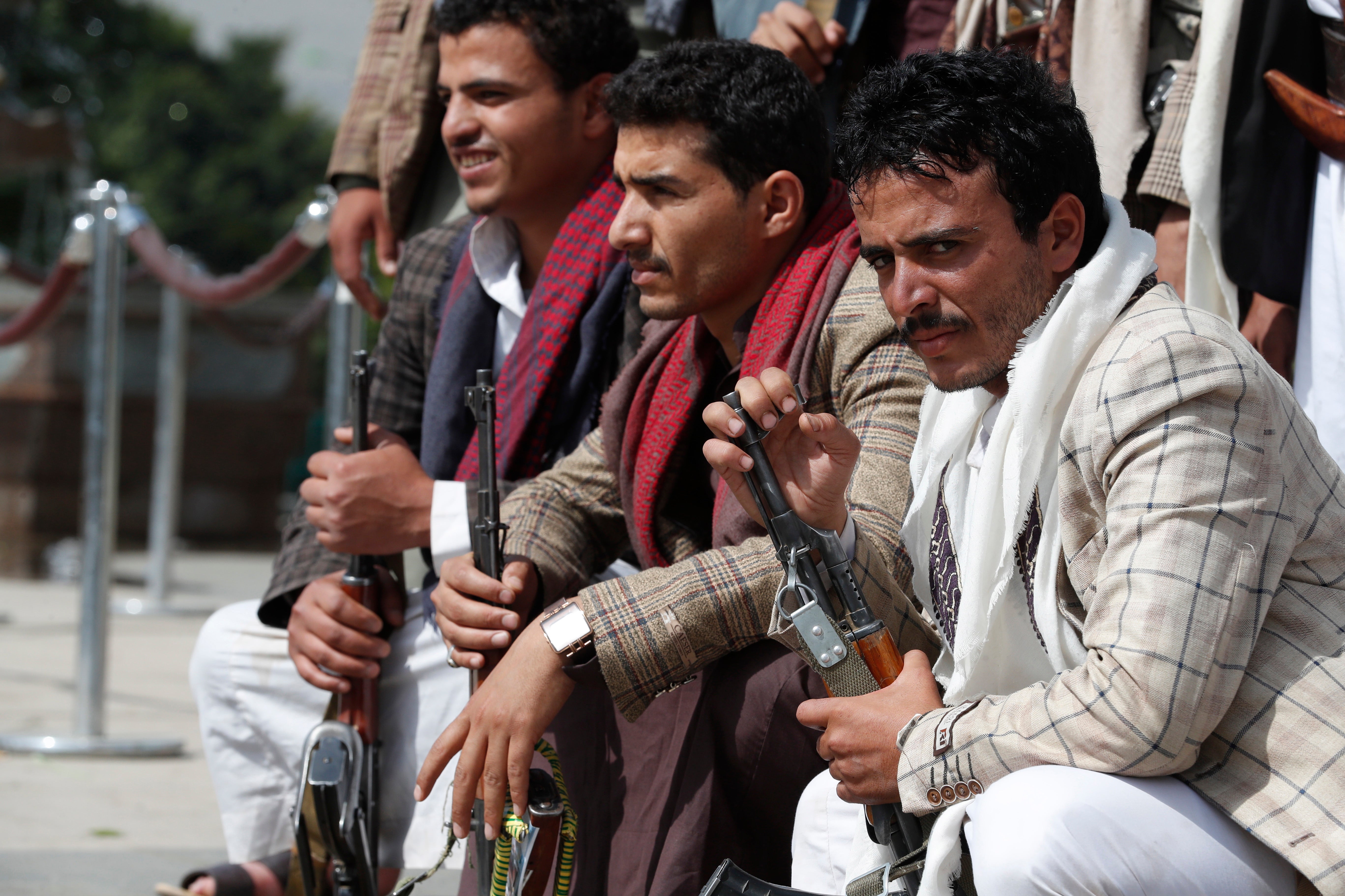 Houthi-allied tribesmen hold weapons as they visit the graves of late Houthis a day after a missile attack on a military base in southern Yemen