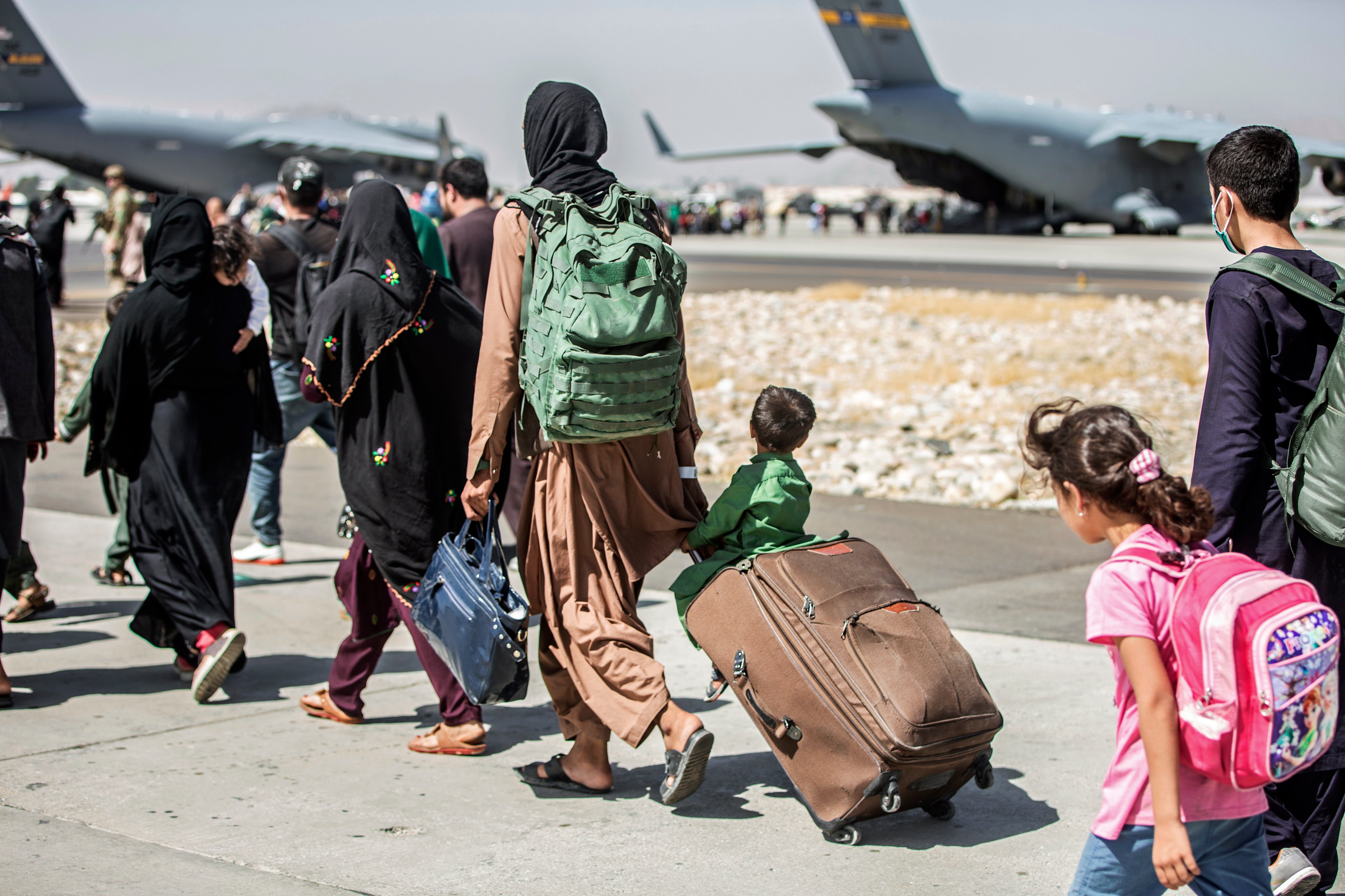 Afghan families form a queue to leave the country on a US military flight