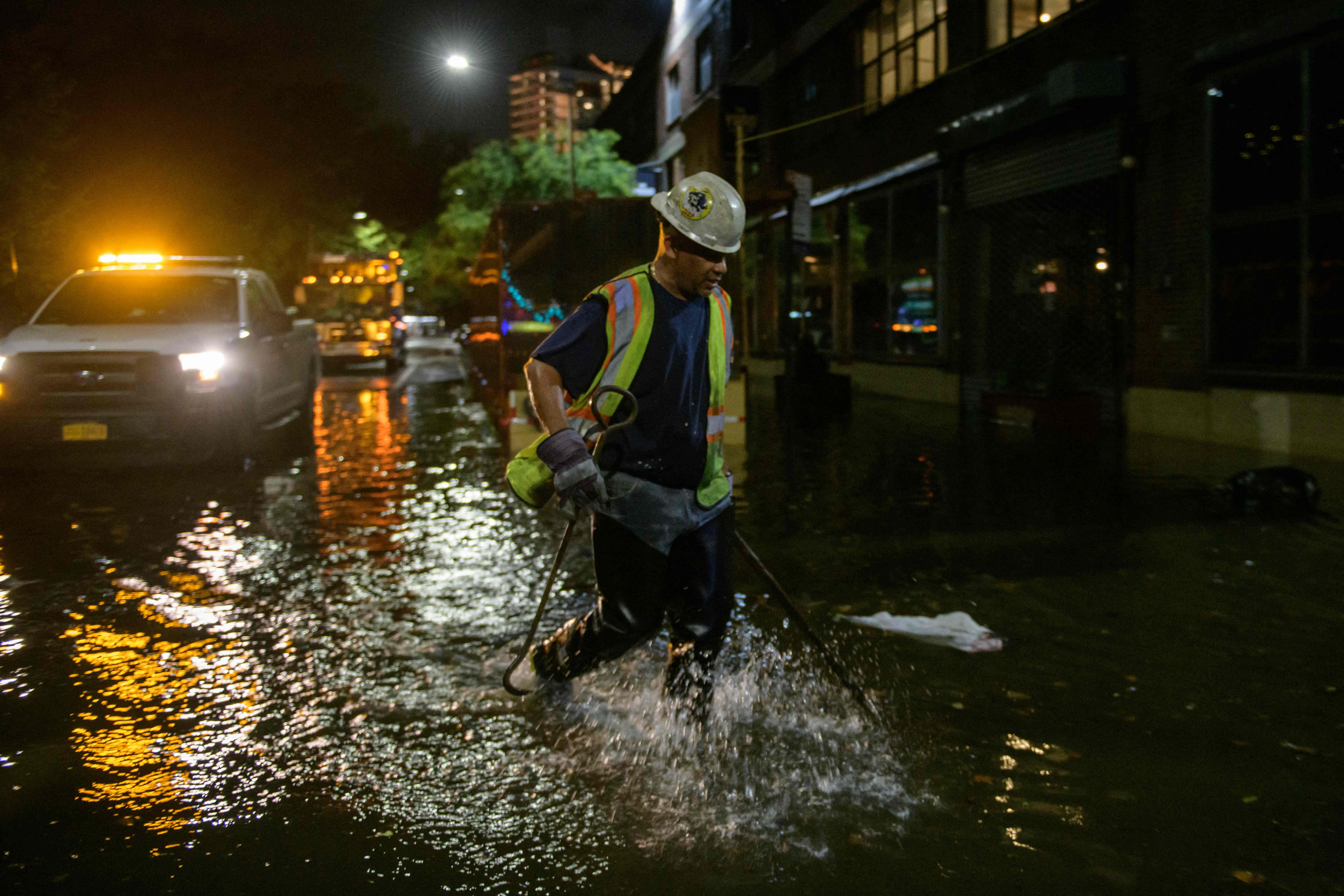 A worker unblocks drains on a street affected by floodwater in Brooklyn, New York early on Thursday