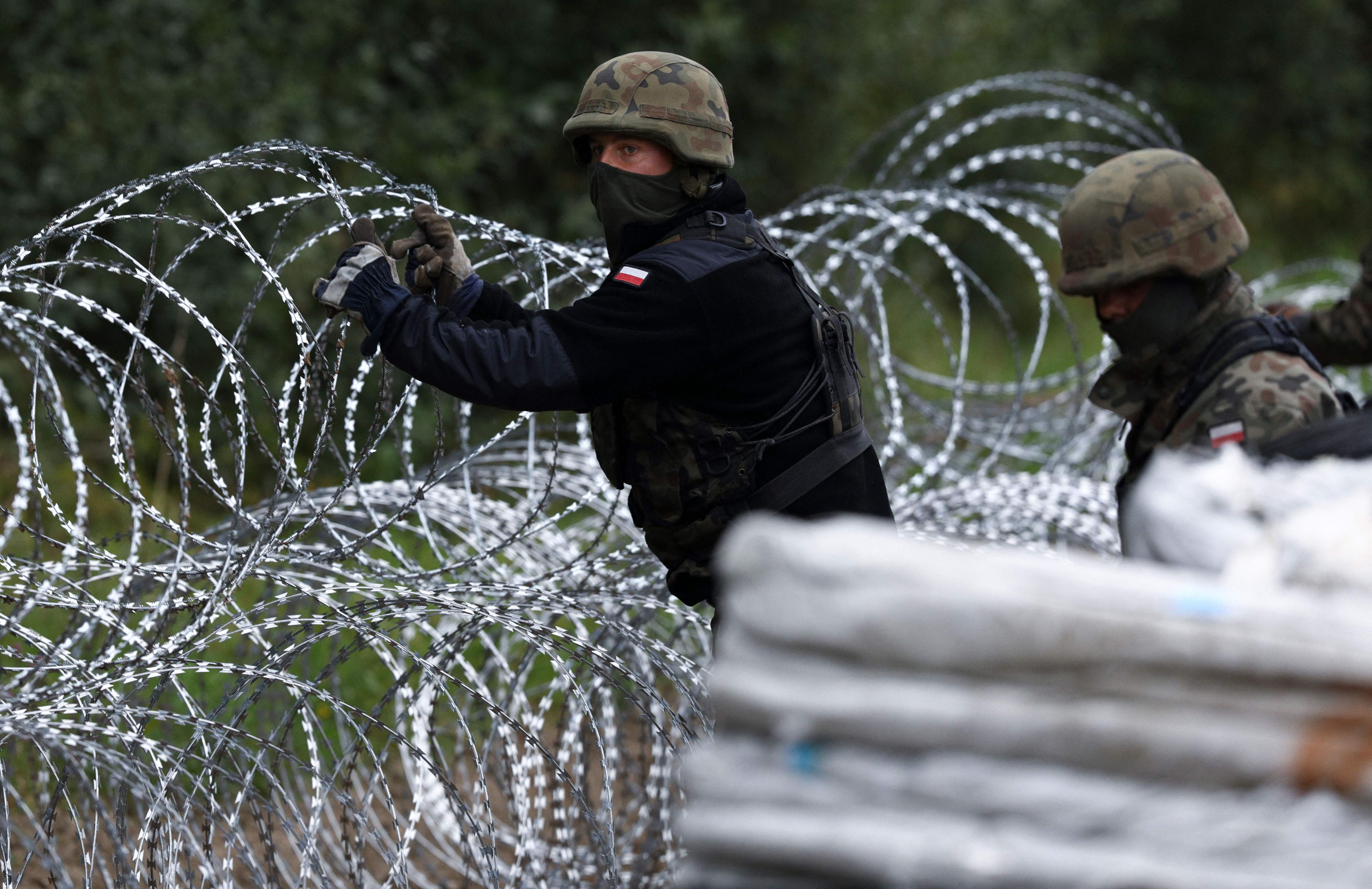 Polish soldiers construct a barbed wire fence on the border with Belarus in Zubrzyca Wielka near Bialystok, eastern Poland, on 26 August 2021