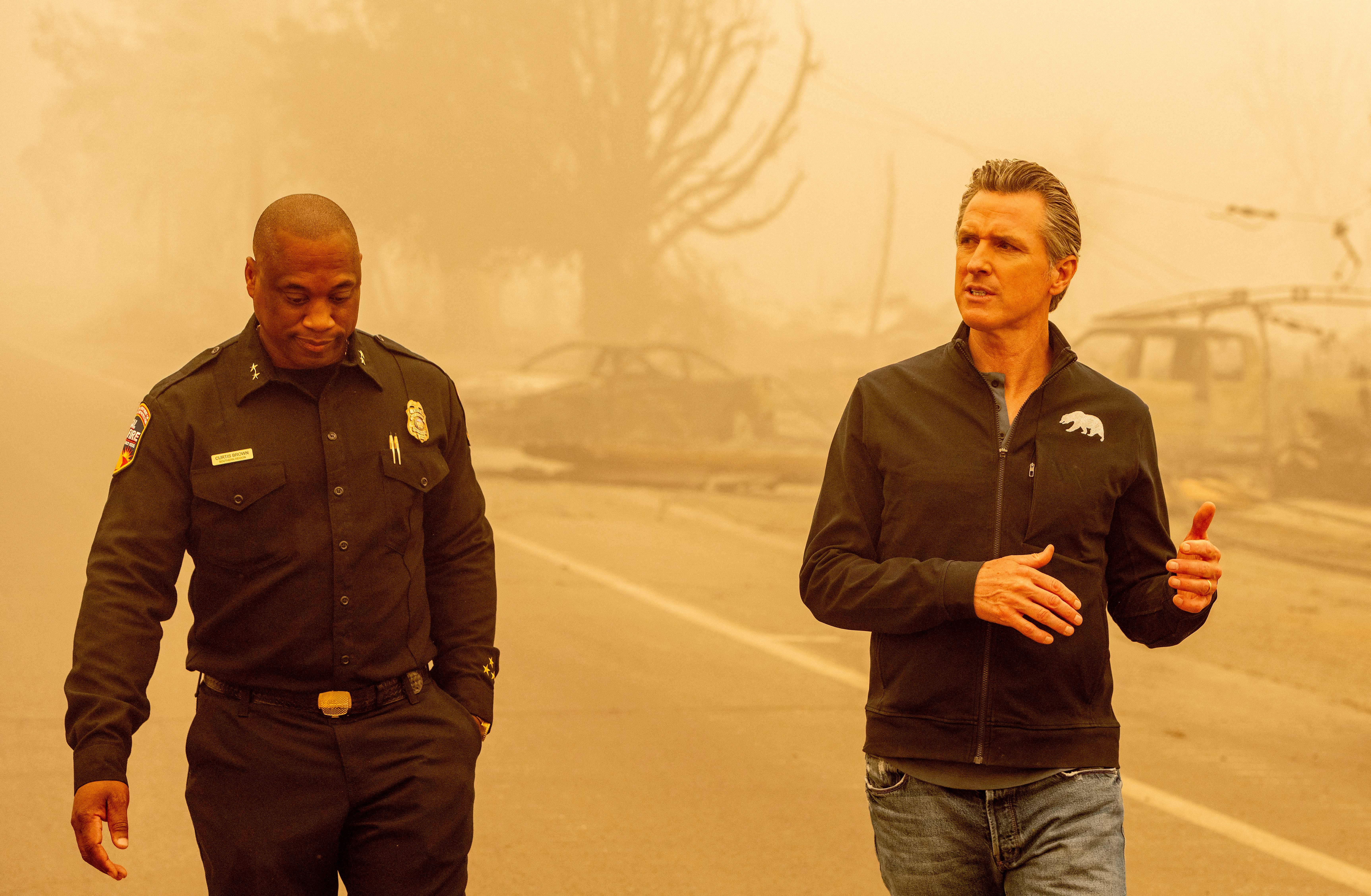 Gavin Newsom walks with Assistant Region Chief for Cal Fire Curtis Brown in downtown Greenville, California on August 7, 2021