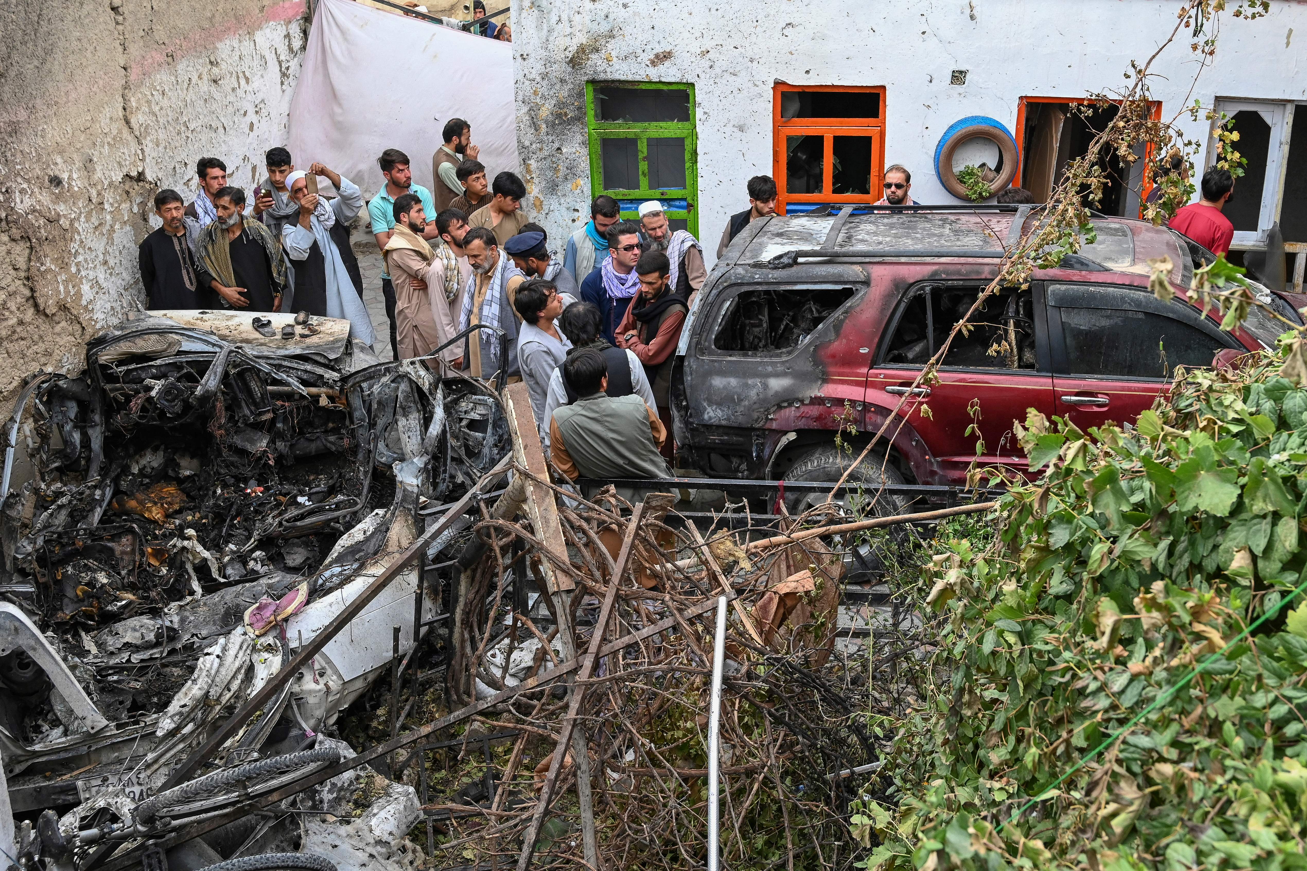 Afghan residents and family members of the victims gather next to a damaged vehicle inside a house, day after a US drone airstrike in Kabul on August 30