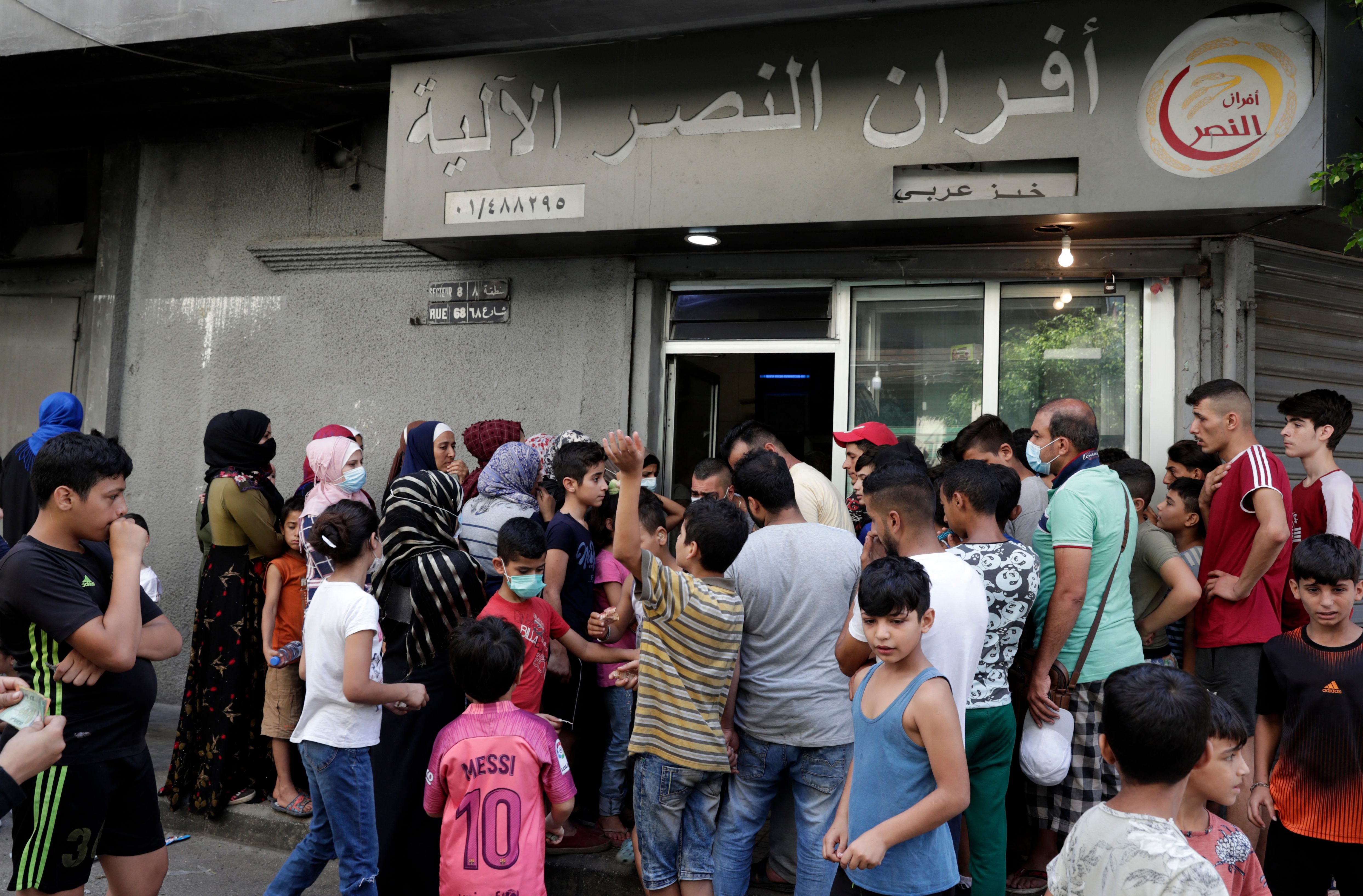 People queue in front of a bakery, in the neighbourhood of Nabaa in the Lebanese capital Beirut's southern suburbs