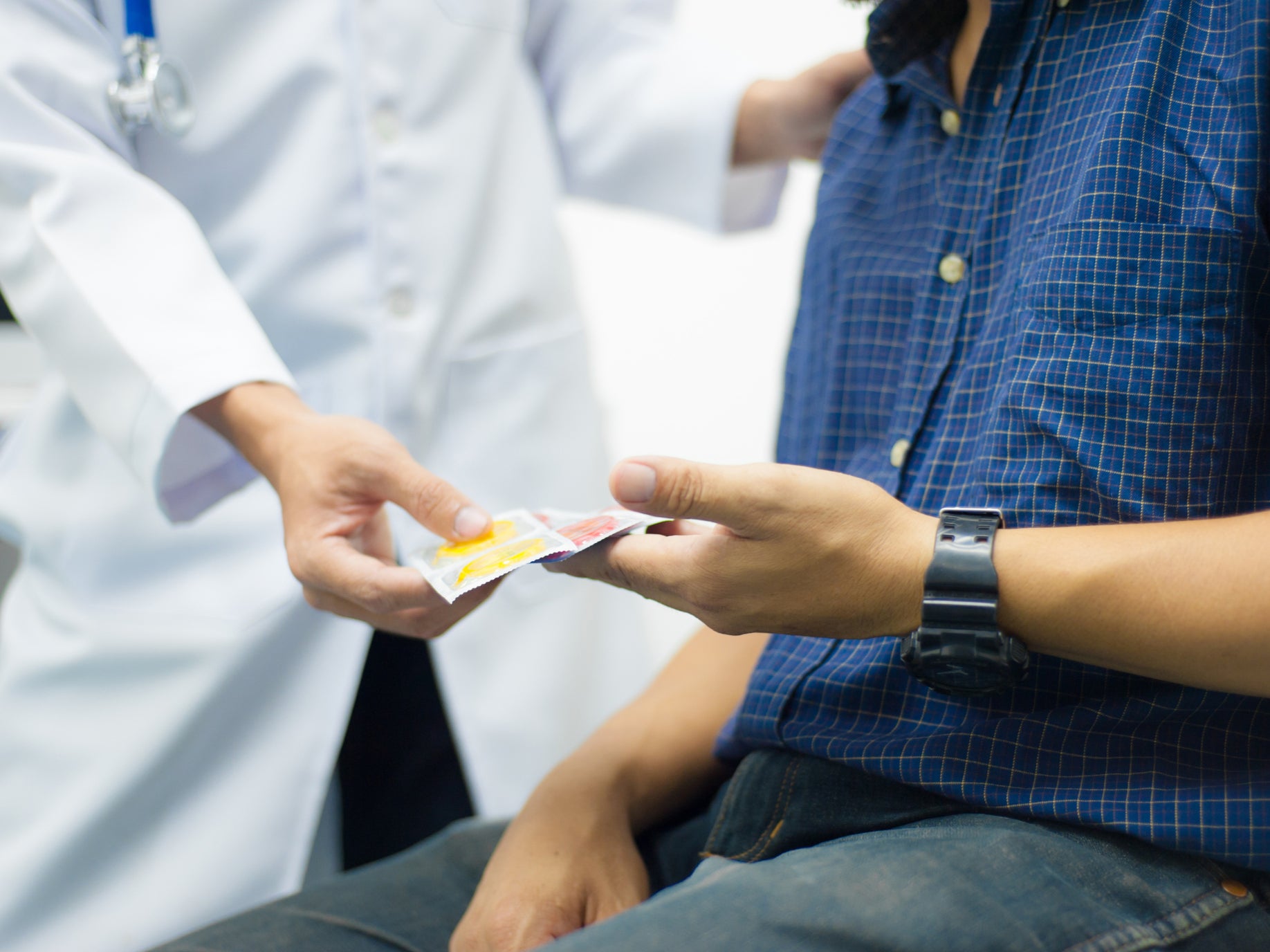 A doctor hands a man a condom