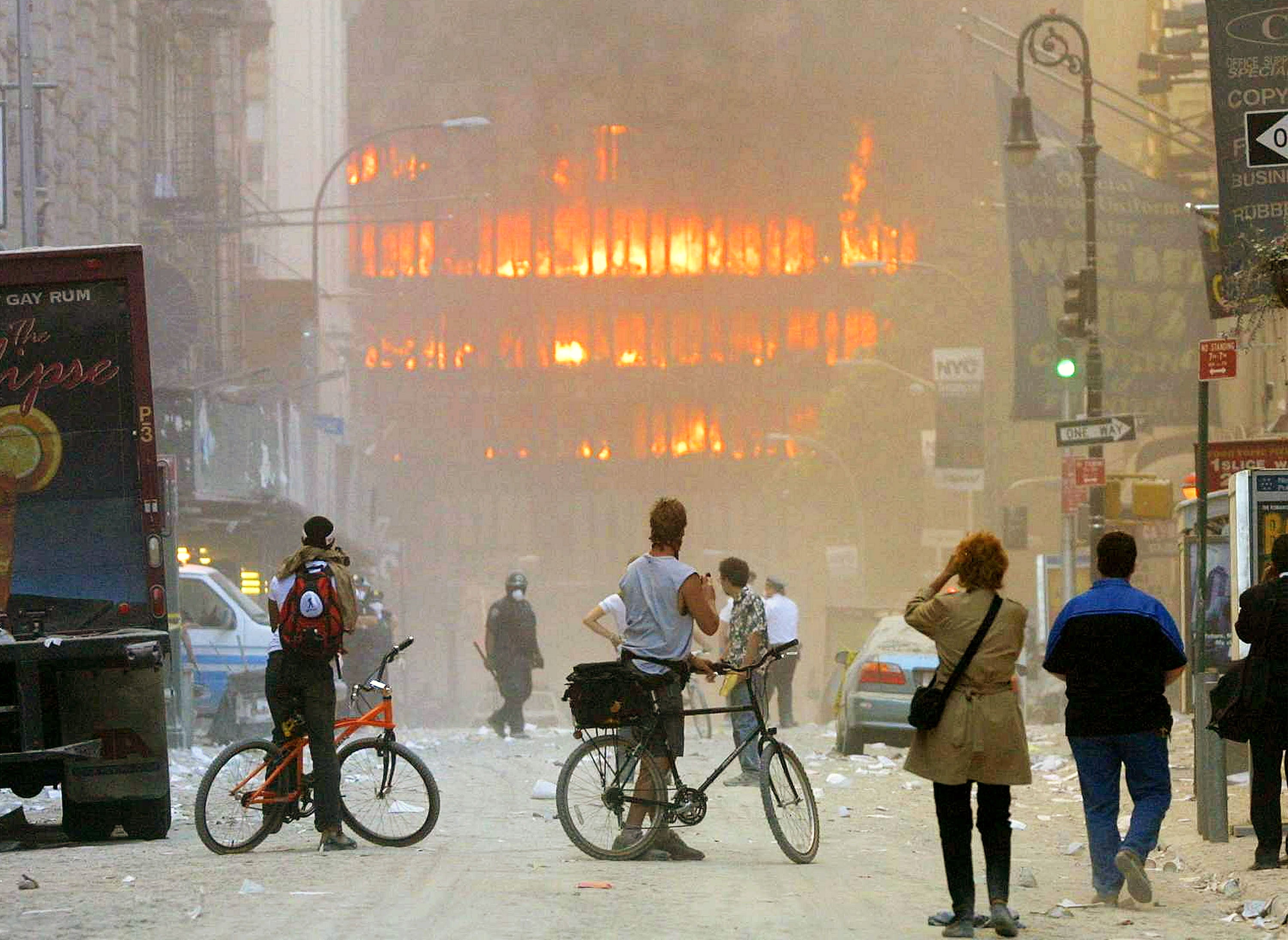 People look down the street at the World Trade Center in flames