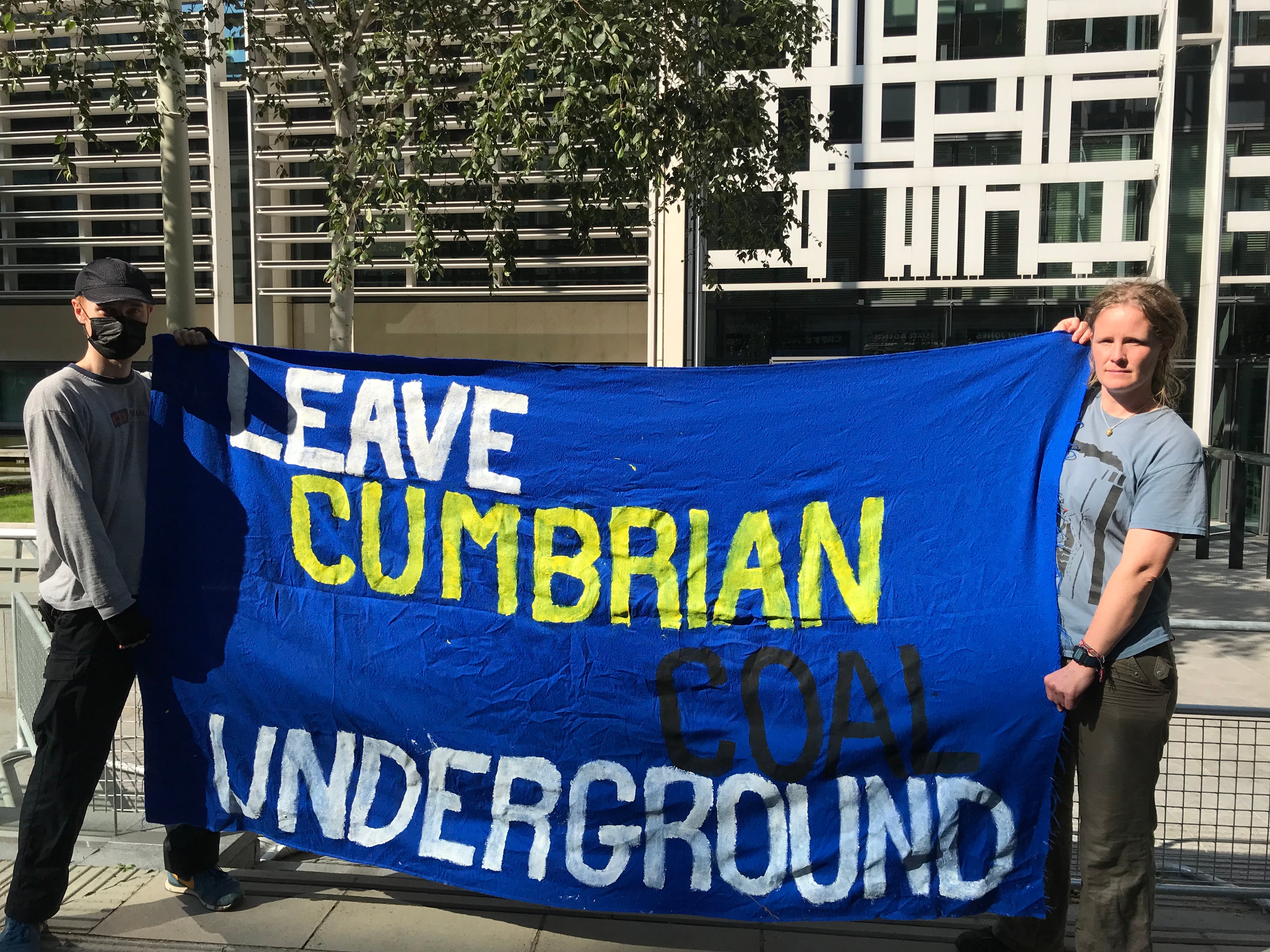 Anne Harris (R) holds a banner outside a government building in the capital.