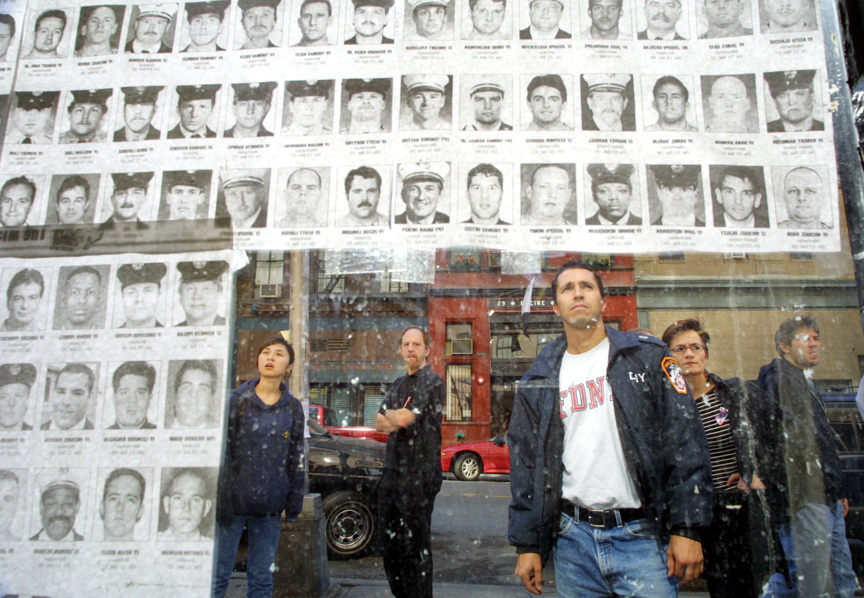 Pedestrians look at photos of missing police and fire personnel missing a couple of weeks after the attacks