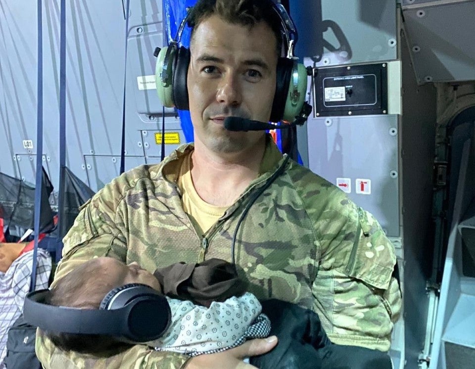 Sgt Andy Livingstone holding a baby Afghan girl while she and her mother slept