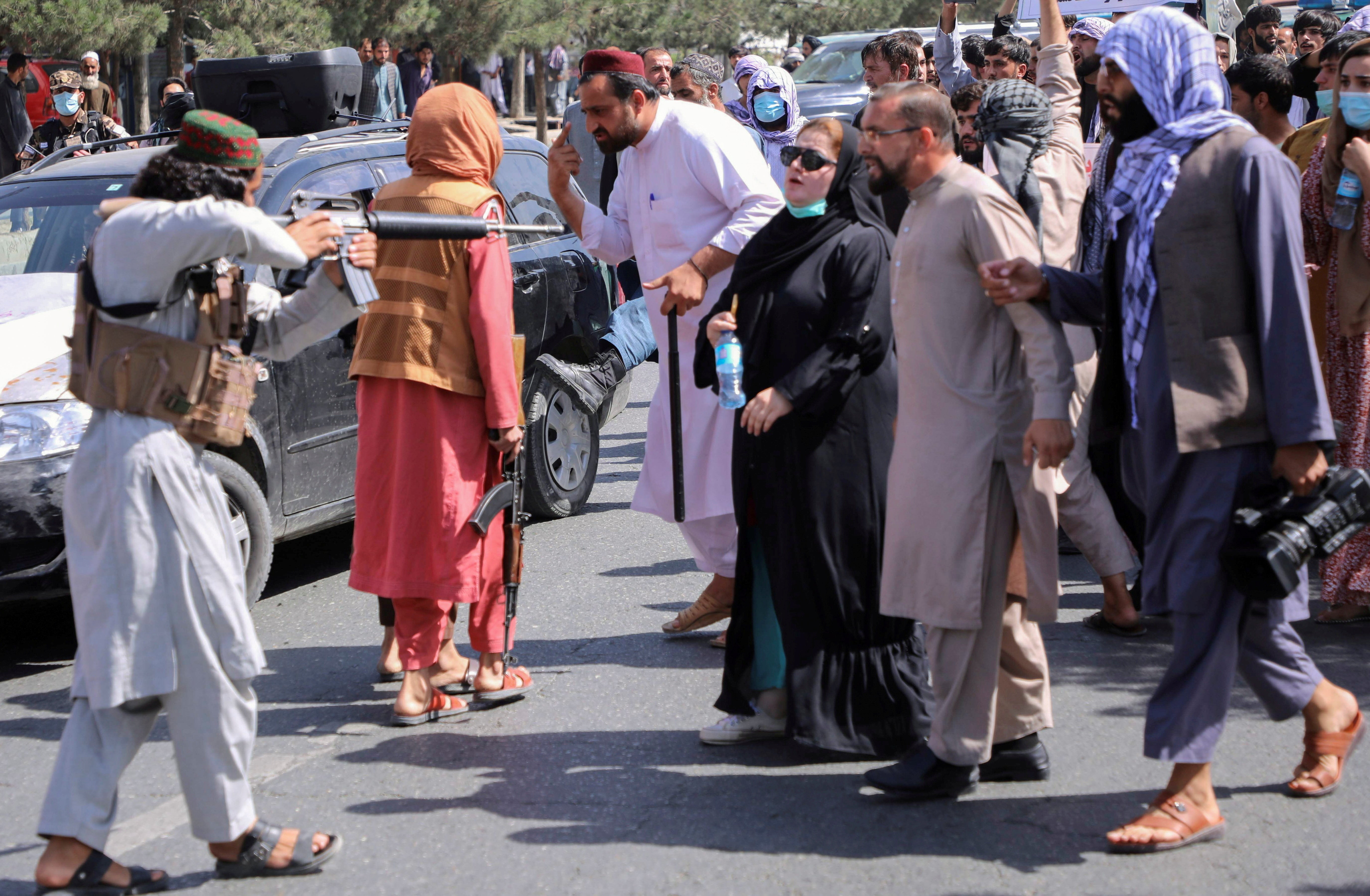 A member of the Taliban forces points his gun at protesters, as Afghan demonstrators shout slogans during an anti-Pakistan protest in Kabul