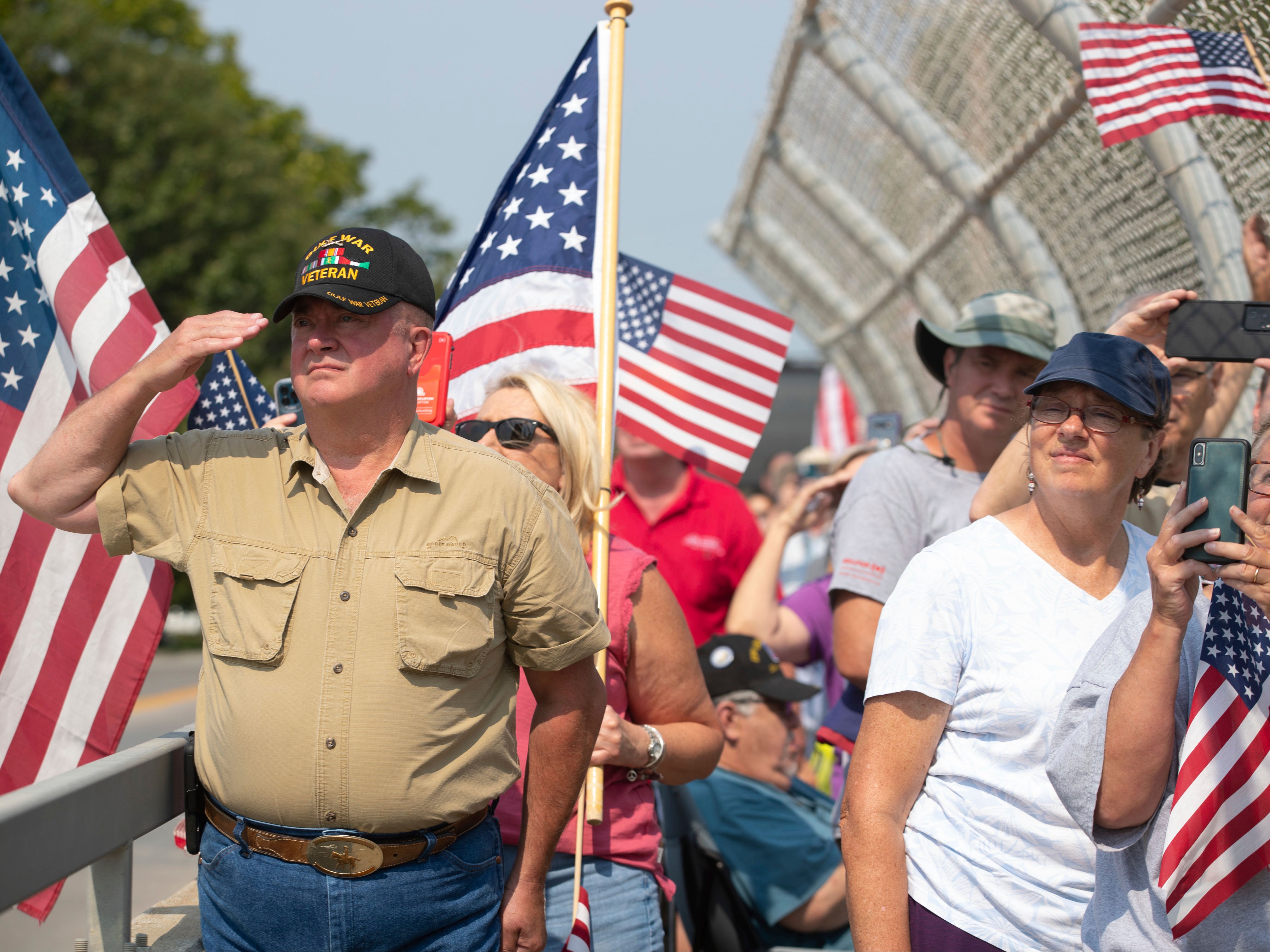 Dean Mathisen, a U.S. Army veteran, salutes, as Omaha Fire and Police Department officials raise an American Flag before Marine Cpl. Daegan Page's procession passes by