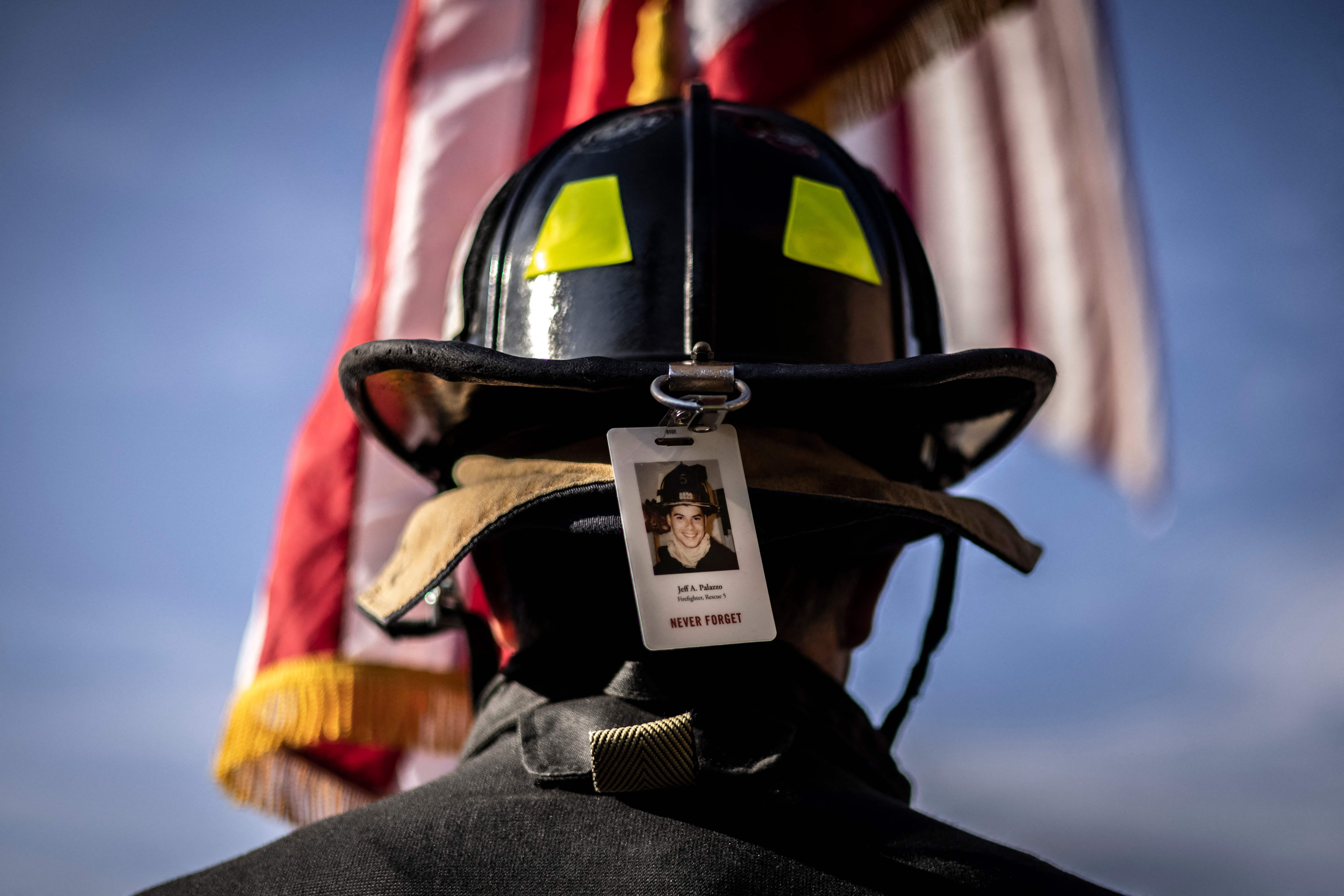 A firefighter wearing the photo badge of a victim on his helmet, pauses for a moment of silence as he participates with first responders, victim's family members and supporters in the 2021 Colorado 9/11 Memorial Stair Climb at the Red Rocks Park and Amphitheatre on September 11, 2021 in Morrison, outside Denver, Colorado. - Participants walk nine laps around the Red Rocks Amphitheater, which is equivalent to the 110 floors of the World Trade Center. (Photo by Chet Strange / AFP) (Photo by CHET STRANGE/AFP via Getty Images)