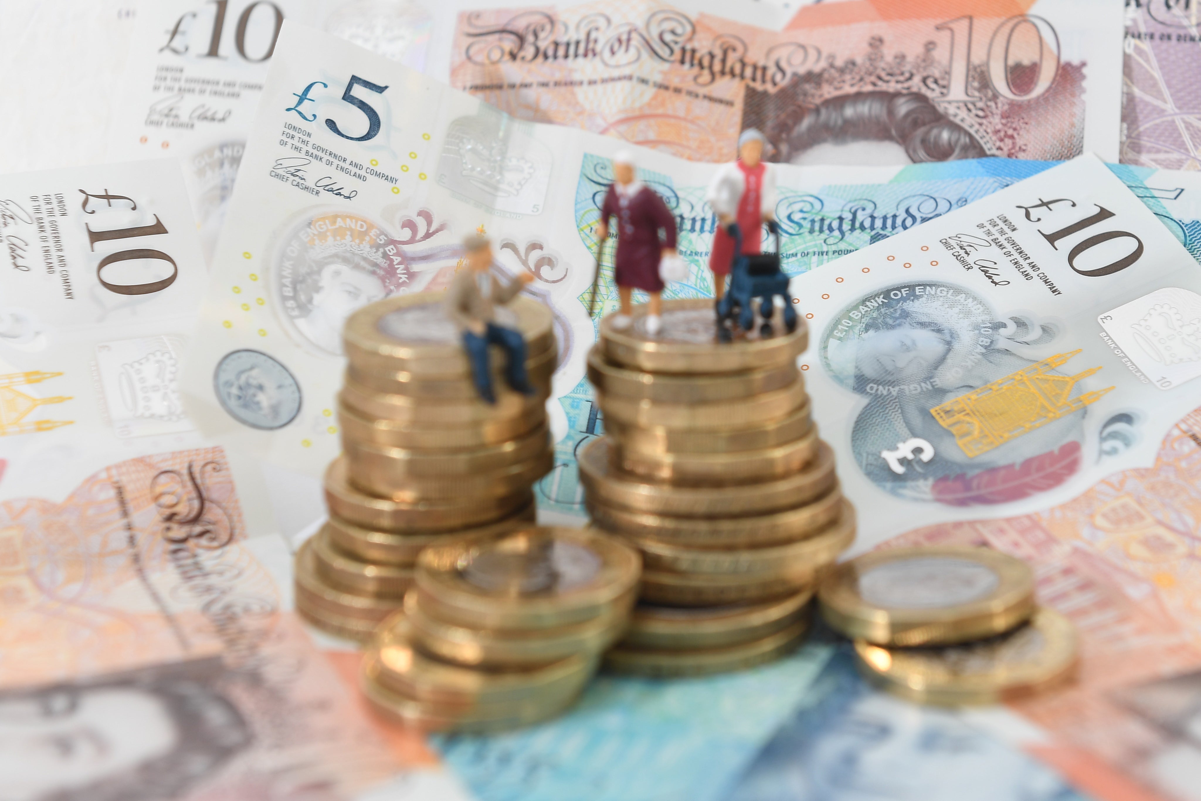 Models of elderly people on a pile of coins and bank notes (Joe Giddens/PA)