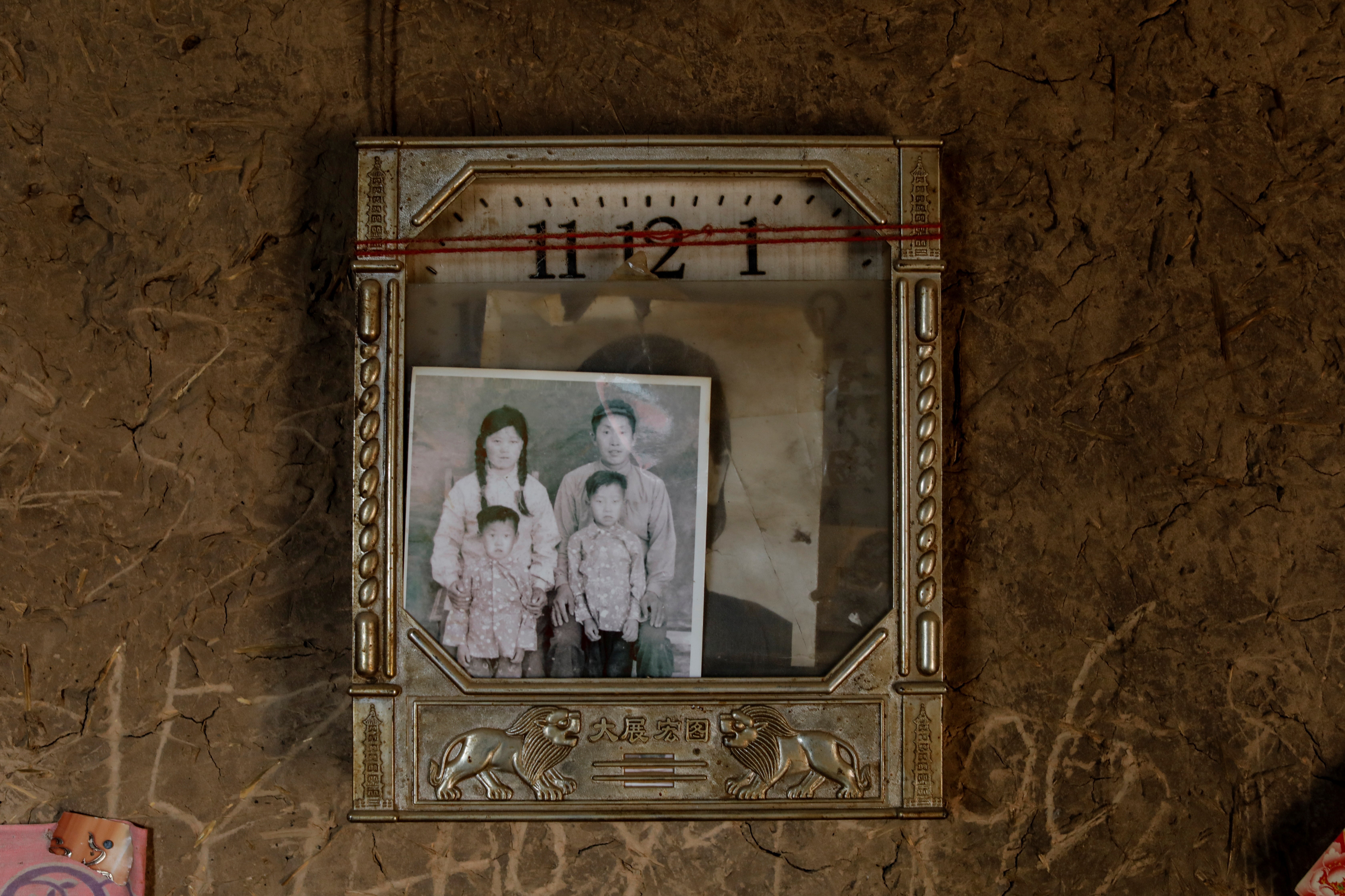 An old family photo placed on a clock is seen at the house of shepherds Ding Yinhua and her husband Li Youfu