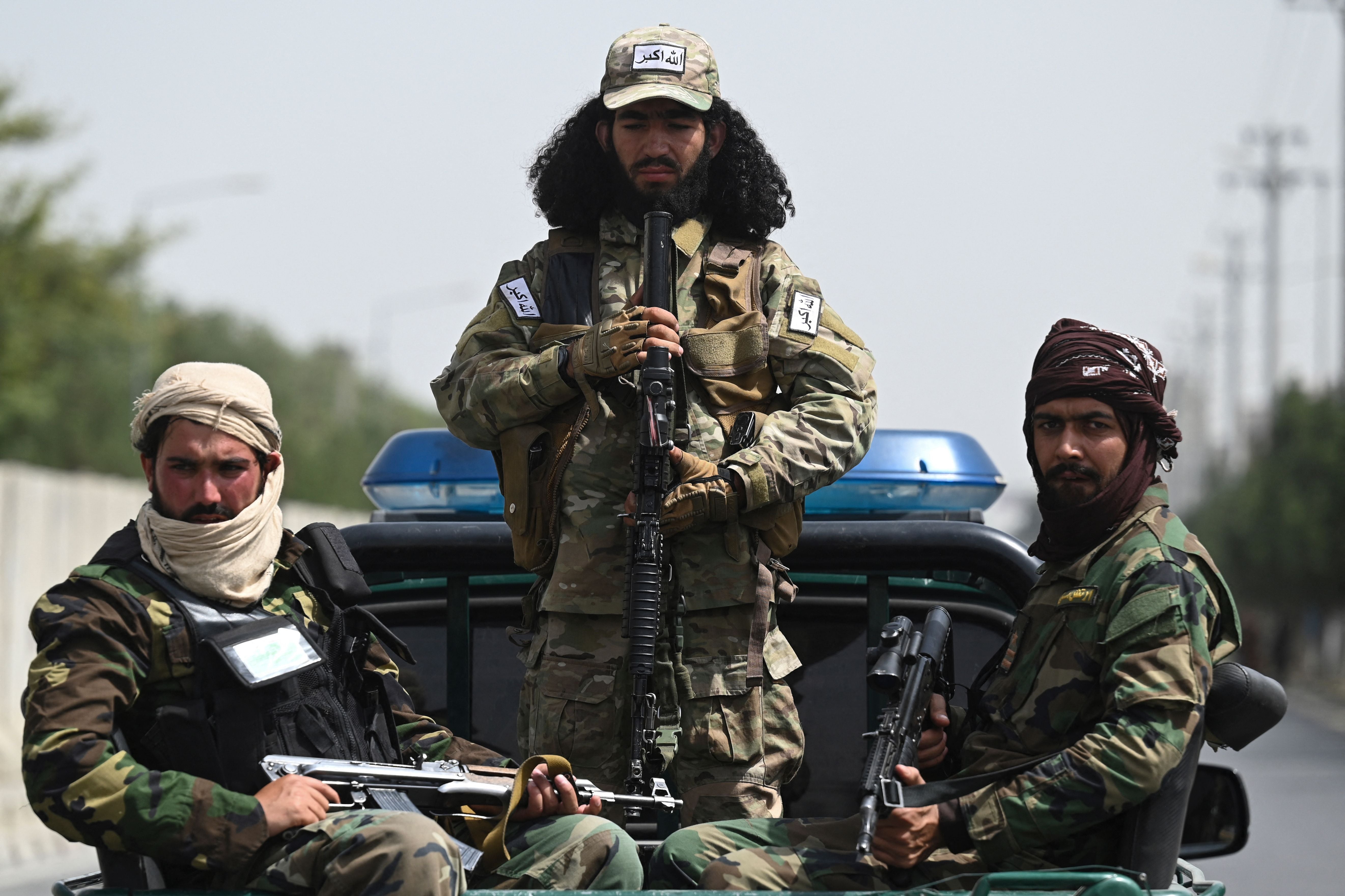 Armed Taliban fighters pictured while veiled women march at a pro-Taliban rally in Kabul on 11 September