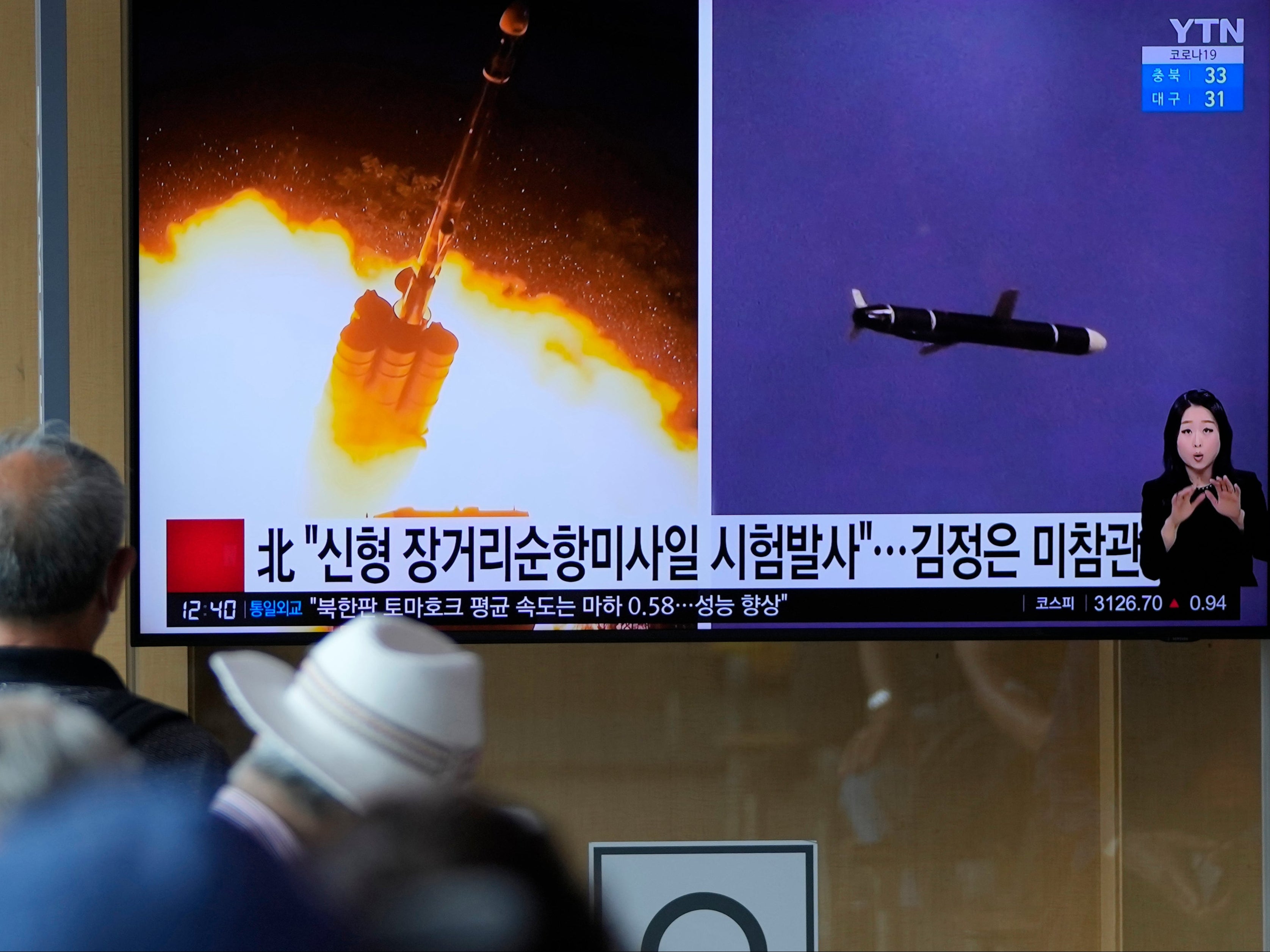 File: People watch a TV screen showing a news programme reporting about North Korea’s long-range cruise missiles tests