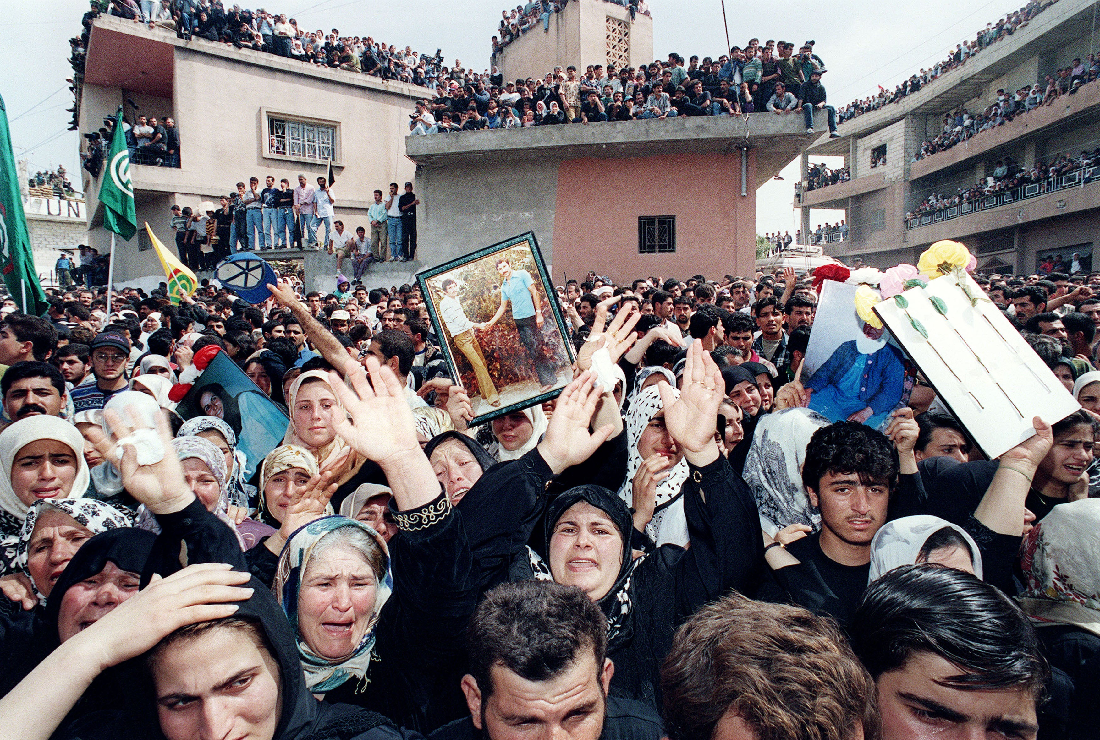 Lebanese Shiites cry holding pictures of their dead relatives during the burial ceremony for 105 civilians