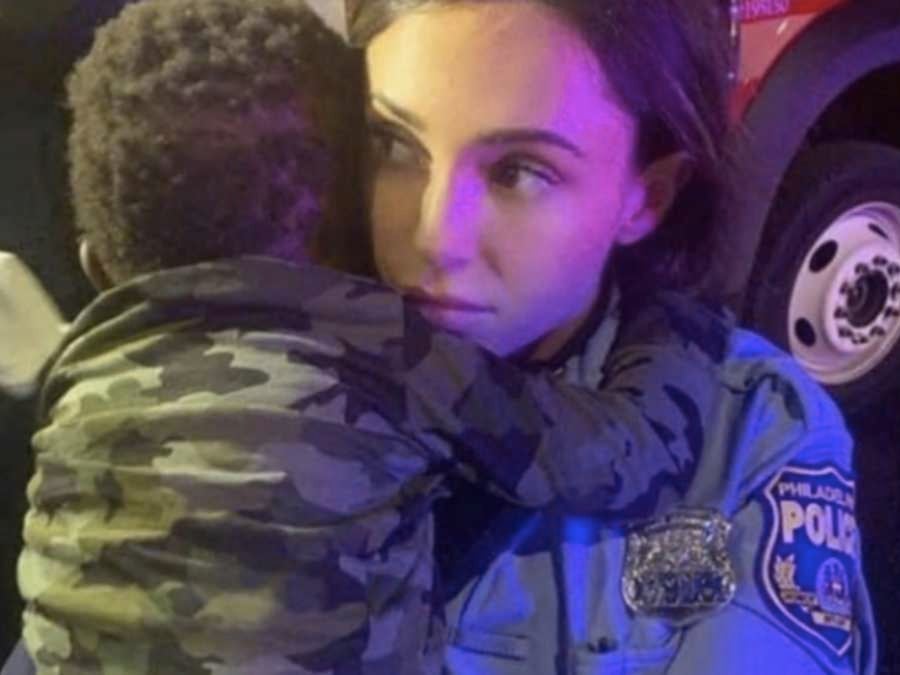 A Philadelphia police officer holding the son of a mother, Rickia Young, who was allegedly beaten during anti-racism demonstrations in Philadelphia last year